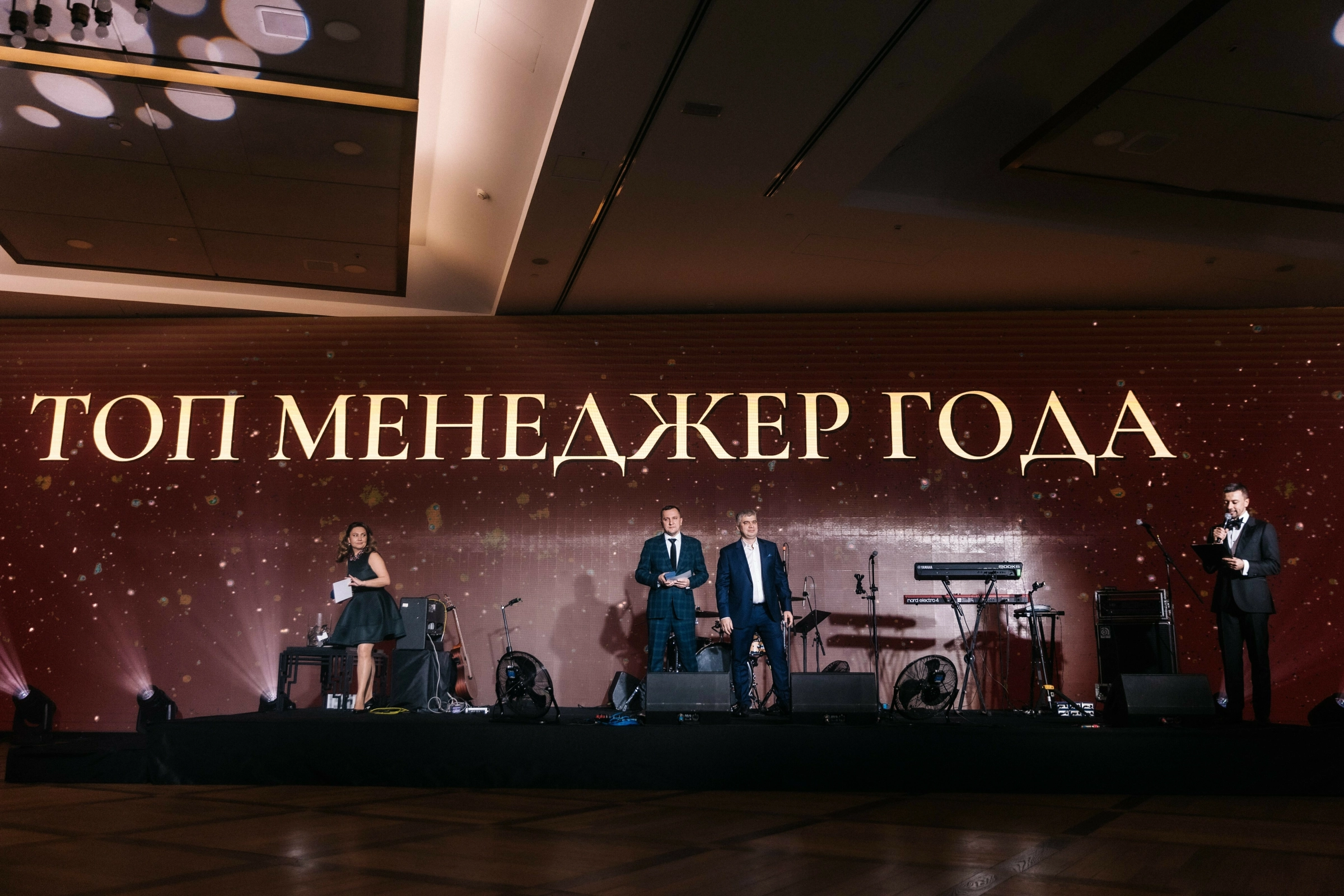 Ведущие и лауреаты на сцене премии с надписью топ менеджер года