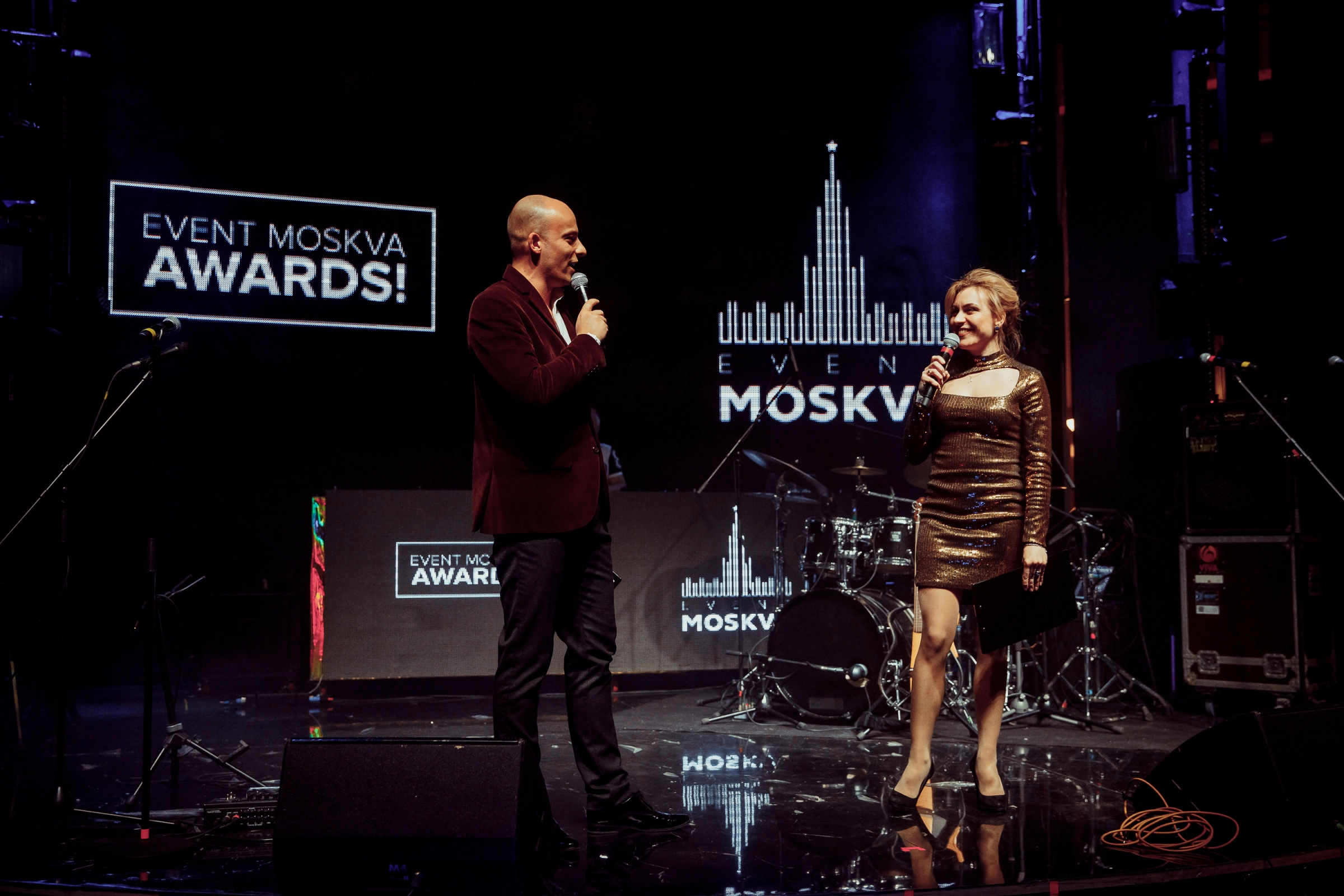 Ведущий и ведущая с микрофонами на сцене премии Event Moskva