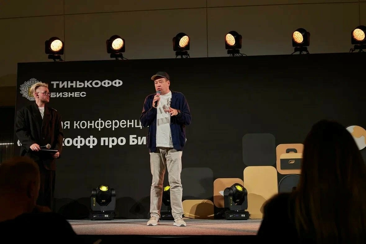 мужчина в кепке выступает с микрофоном на бизнес-конференции