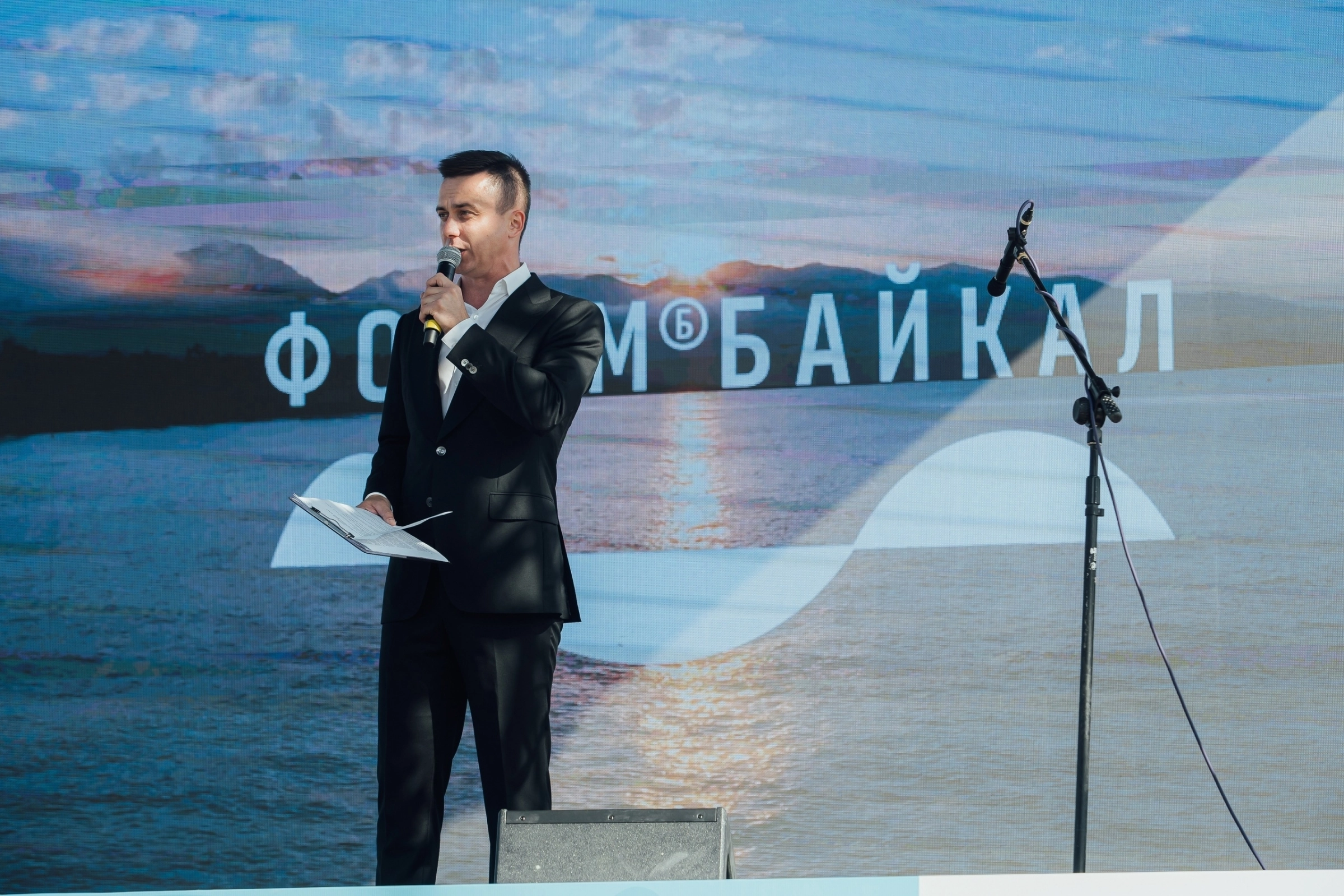 ведущий с микрофоном на фоне яркой круглой световой инсталляции