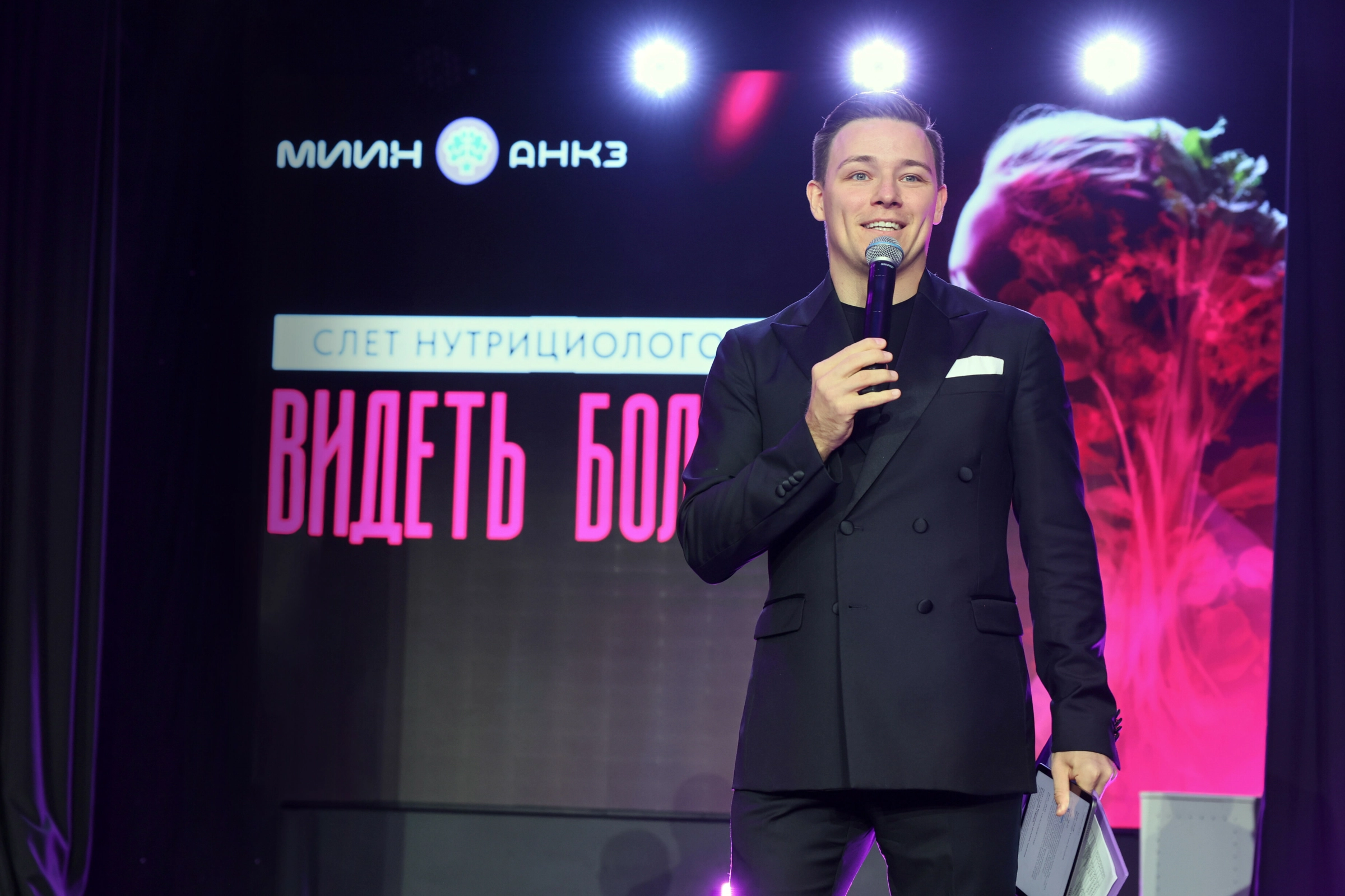 ведущий выступает на сцене тематической конференции для нутрициологов