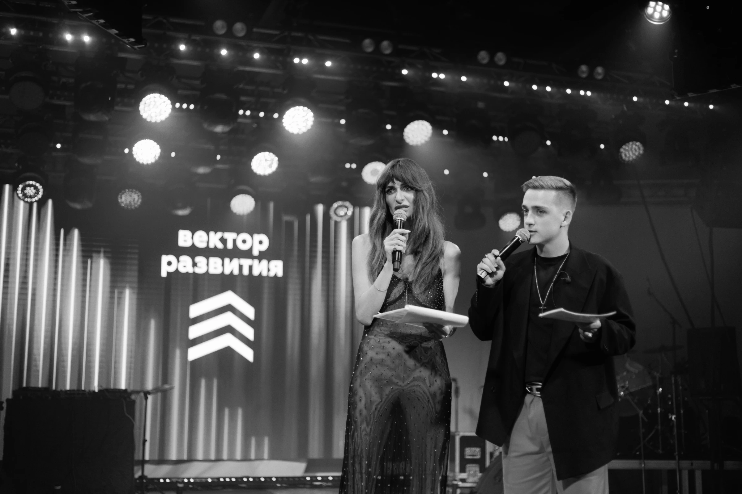 ведущие с микрофонами на сцене корпоративной премии награждения