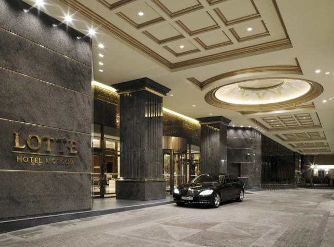 Парадный вход в отель с золотой вывеской Lotte Hotel Moscow и колоннами
