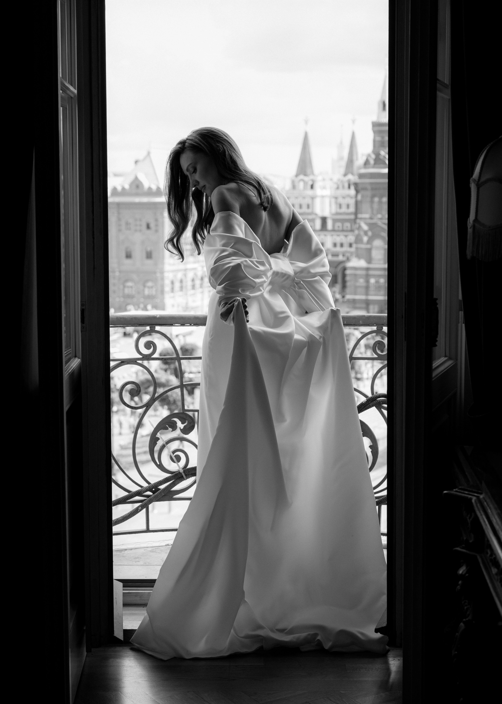 невеста в платье с открытой спиной на балконе с видом на город