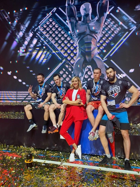 пара ведущих на сцене спортивного форума с прожекторами