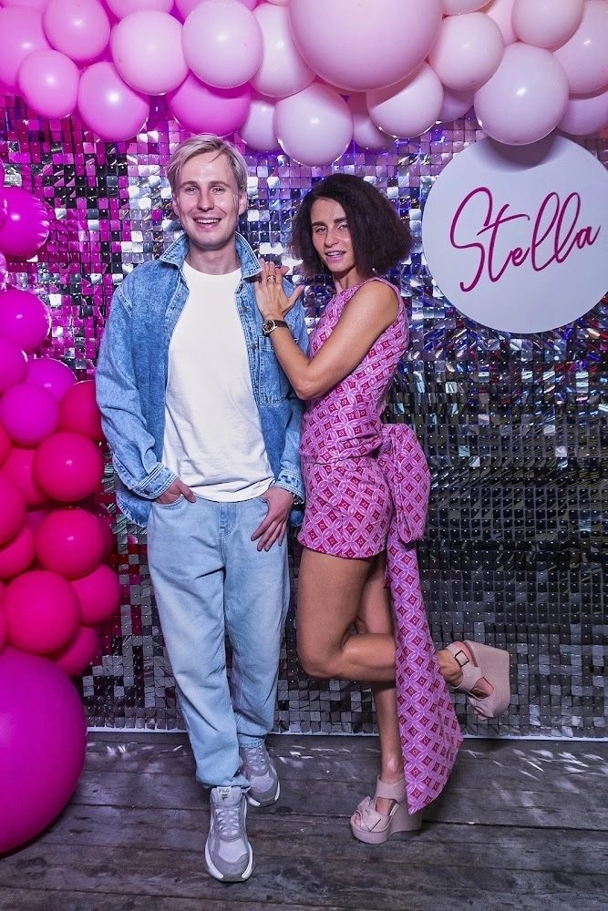 пара позирует у фотозоны с розовыми шарами и вывеской stella