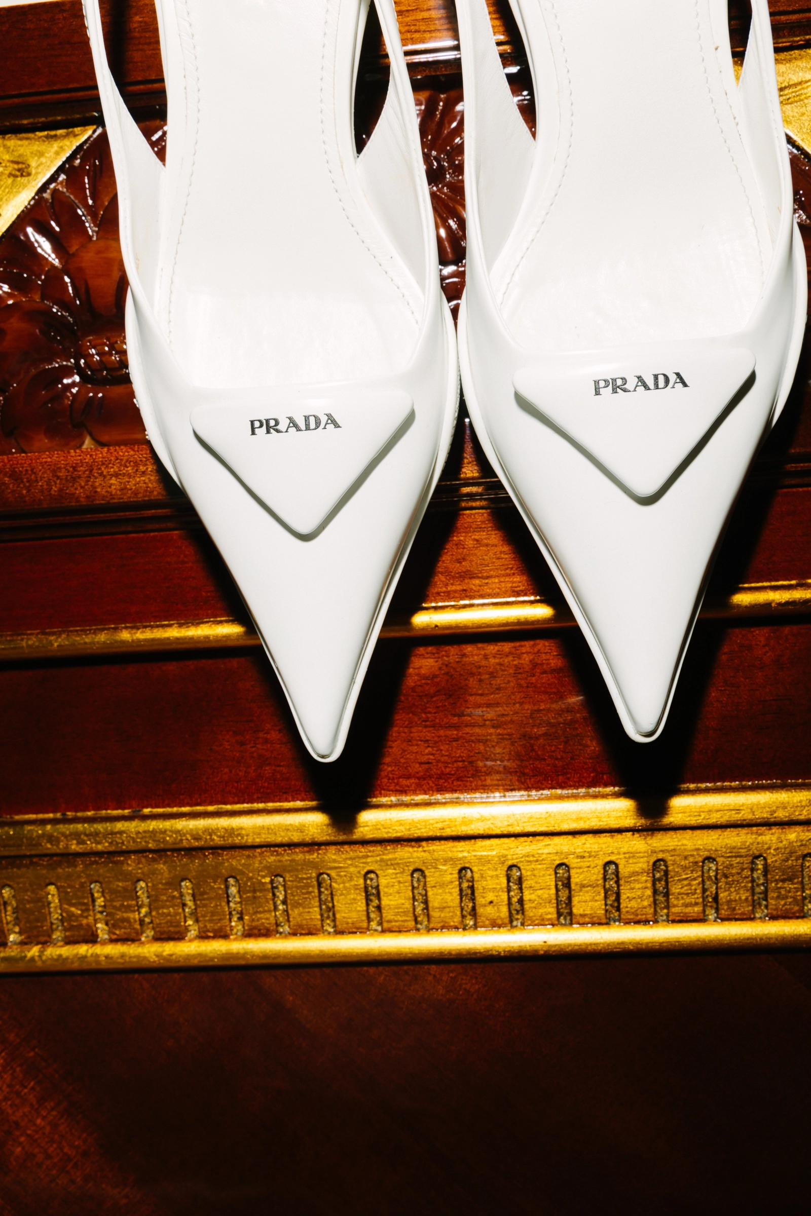 белые остроносые туфли Prada на резном деревянном комоде с позолотой