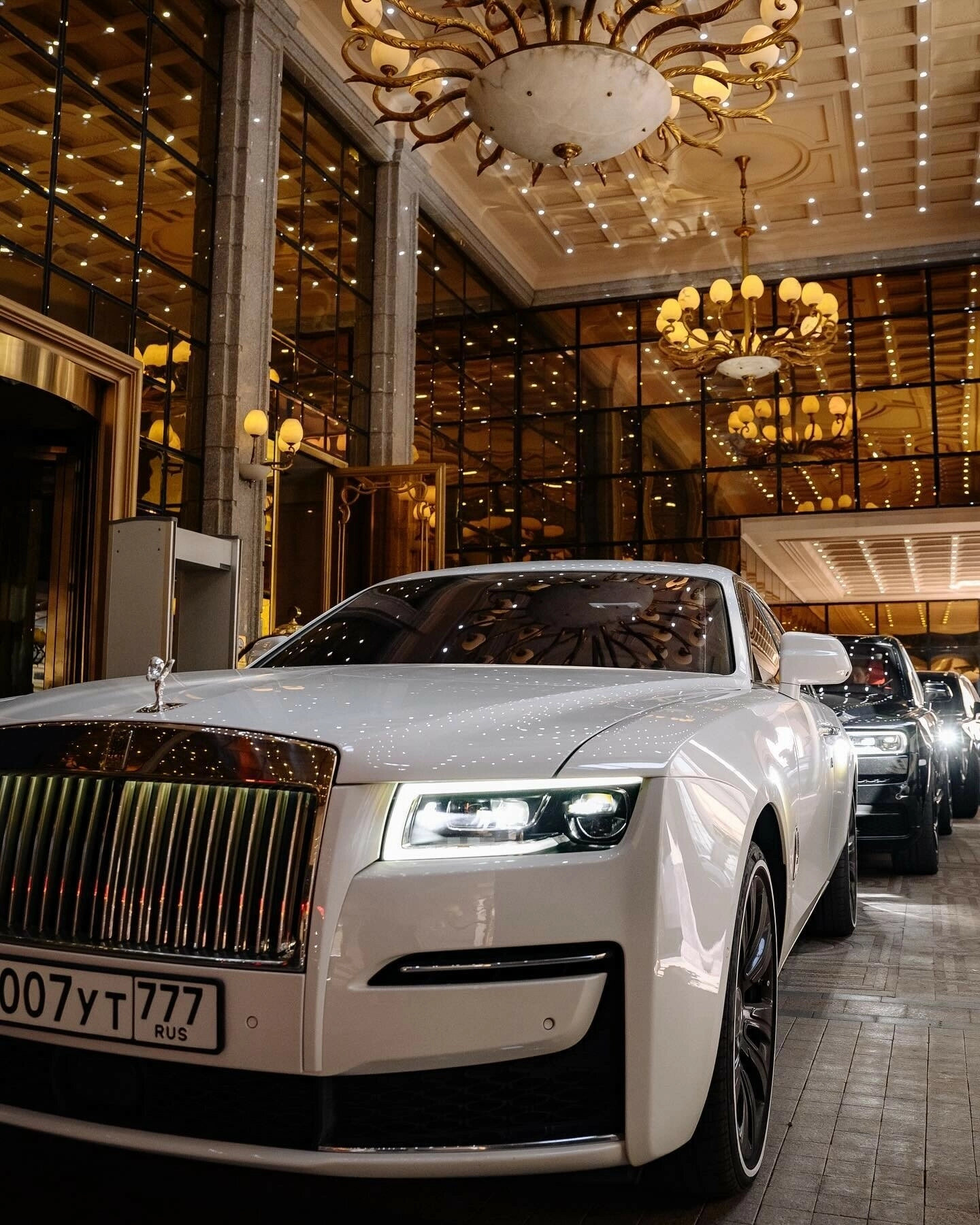 белый Rolls-Royce свадебного кортежа у входа в отель с люстрами