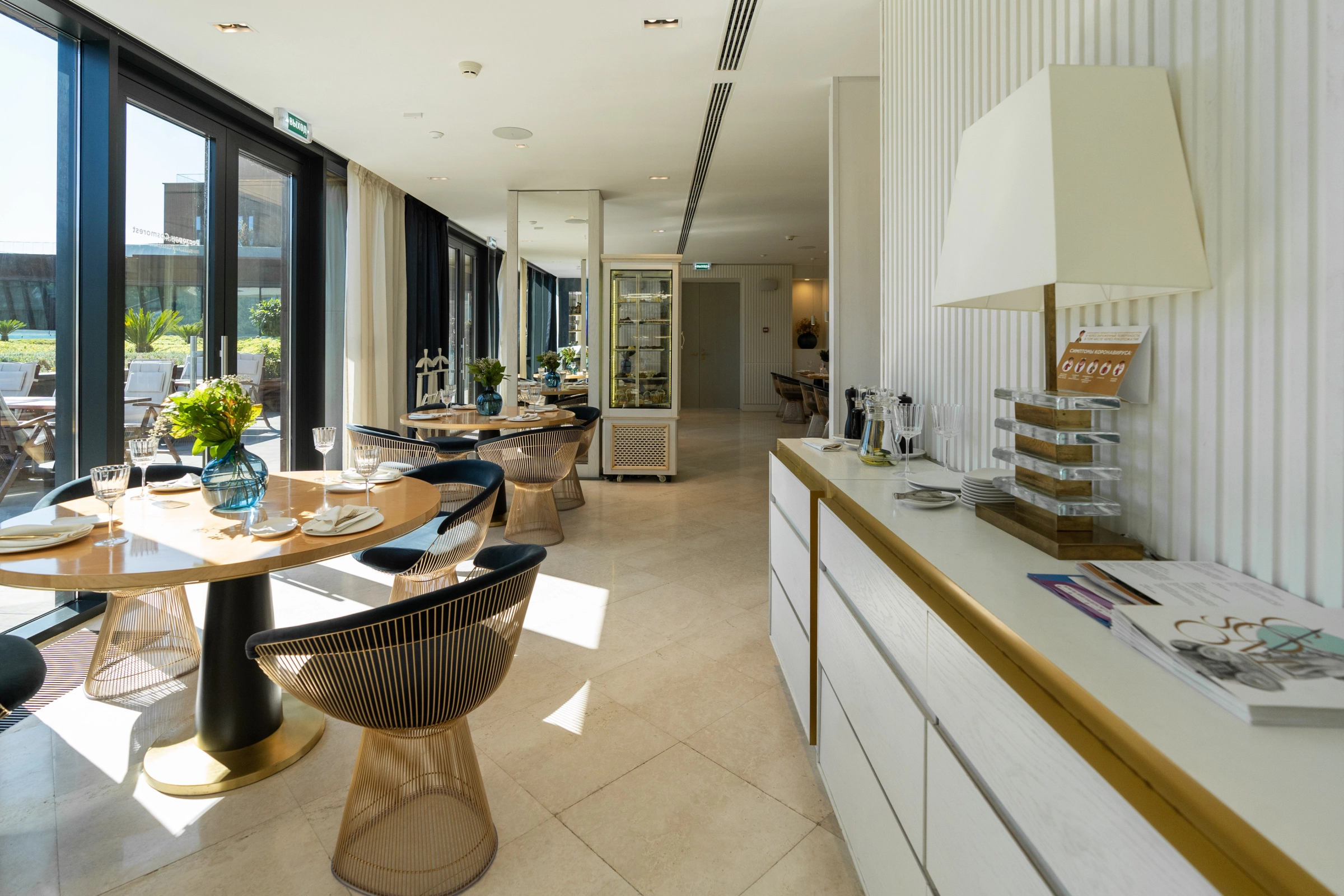 банкетный зал с круглыми столами и золотистыми креслами у панорамных окон