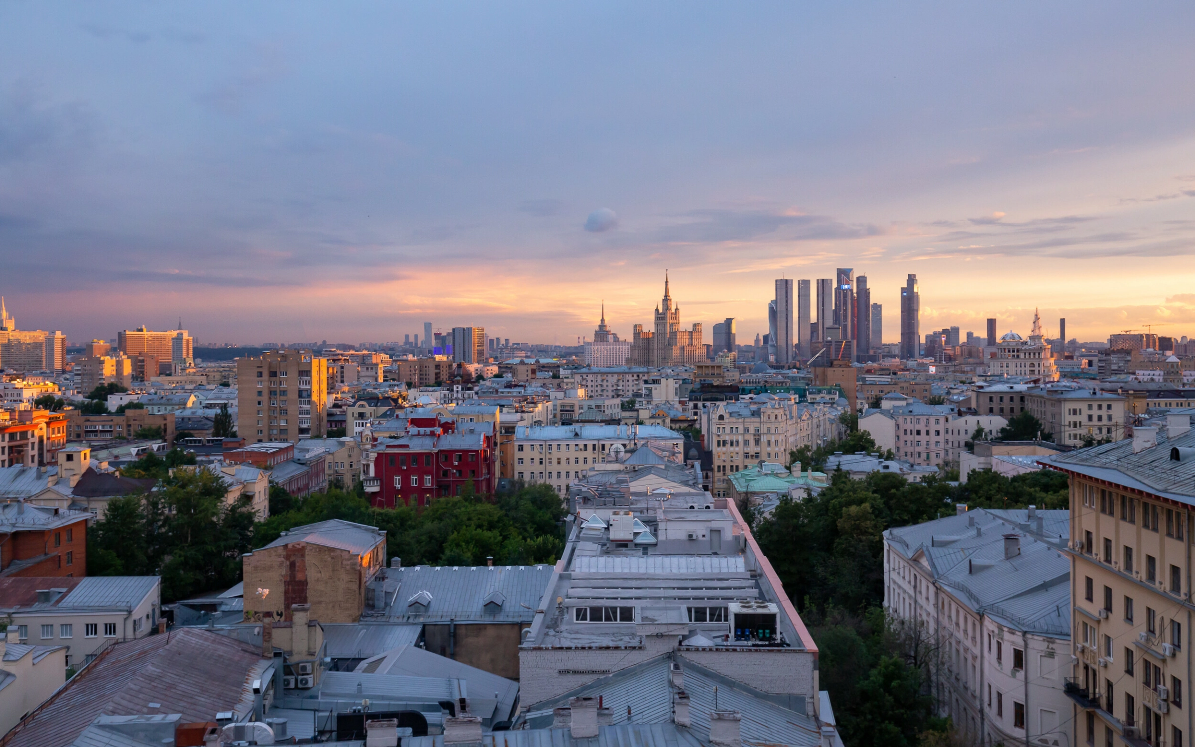 Панорама вечернего города с высотками на фоне заката с крыши отеля