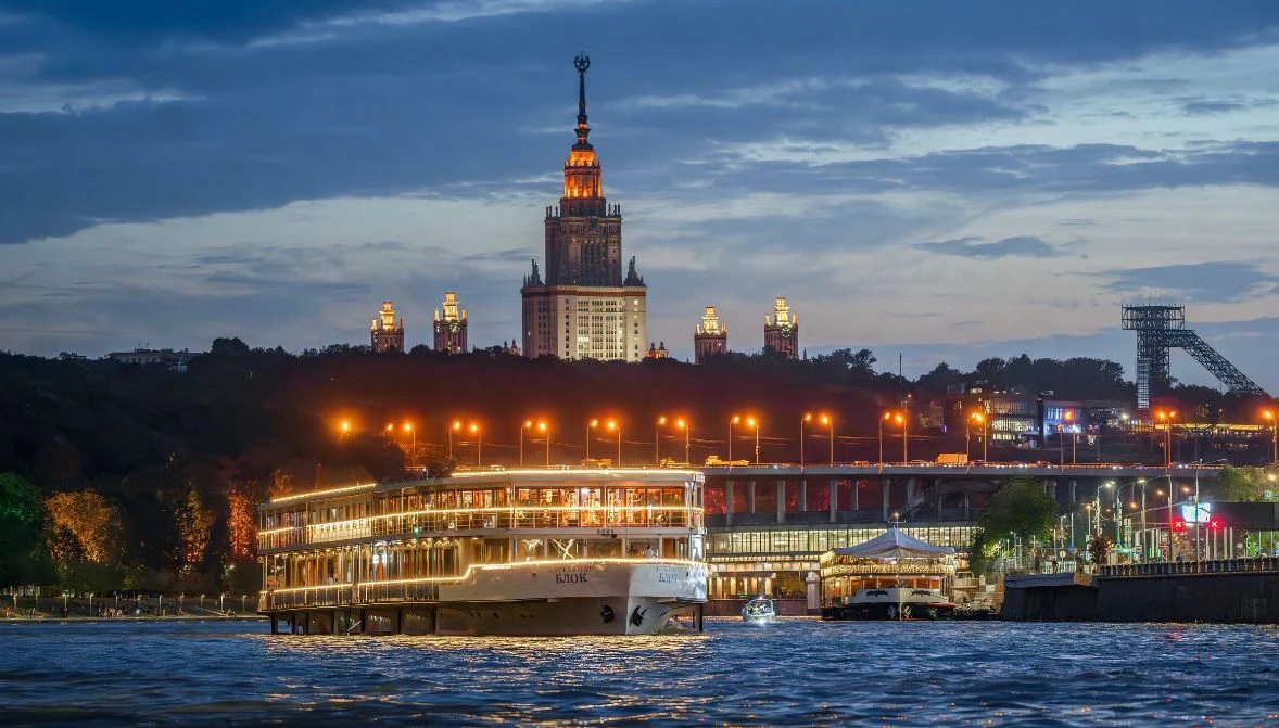 Ночная панорама яхты-ресторана на реке с подсветкой и силуэтом МГУ