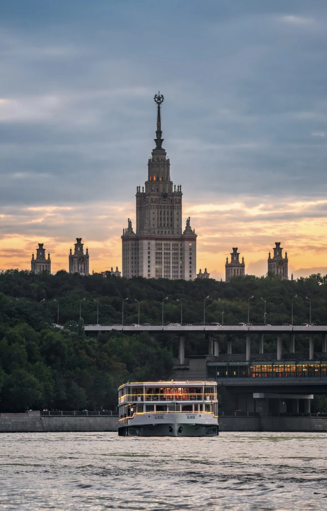 Силуэт высотки МГУ и яхты-ресторана в закатном небе над рекой