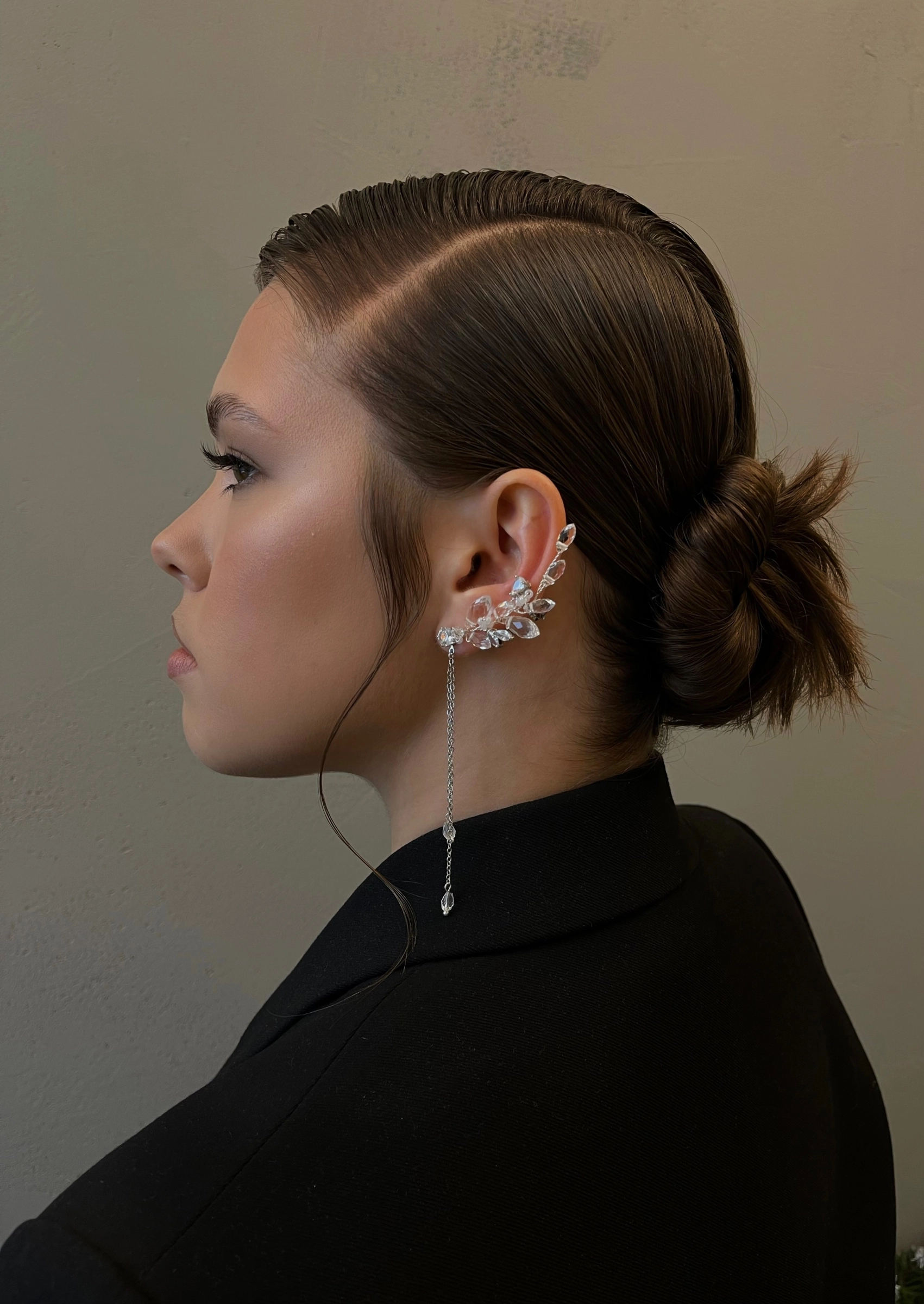 гладкий низкий пучок и серебристый ear cuff с цепочкой в профильном портрете
