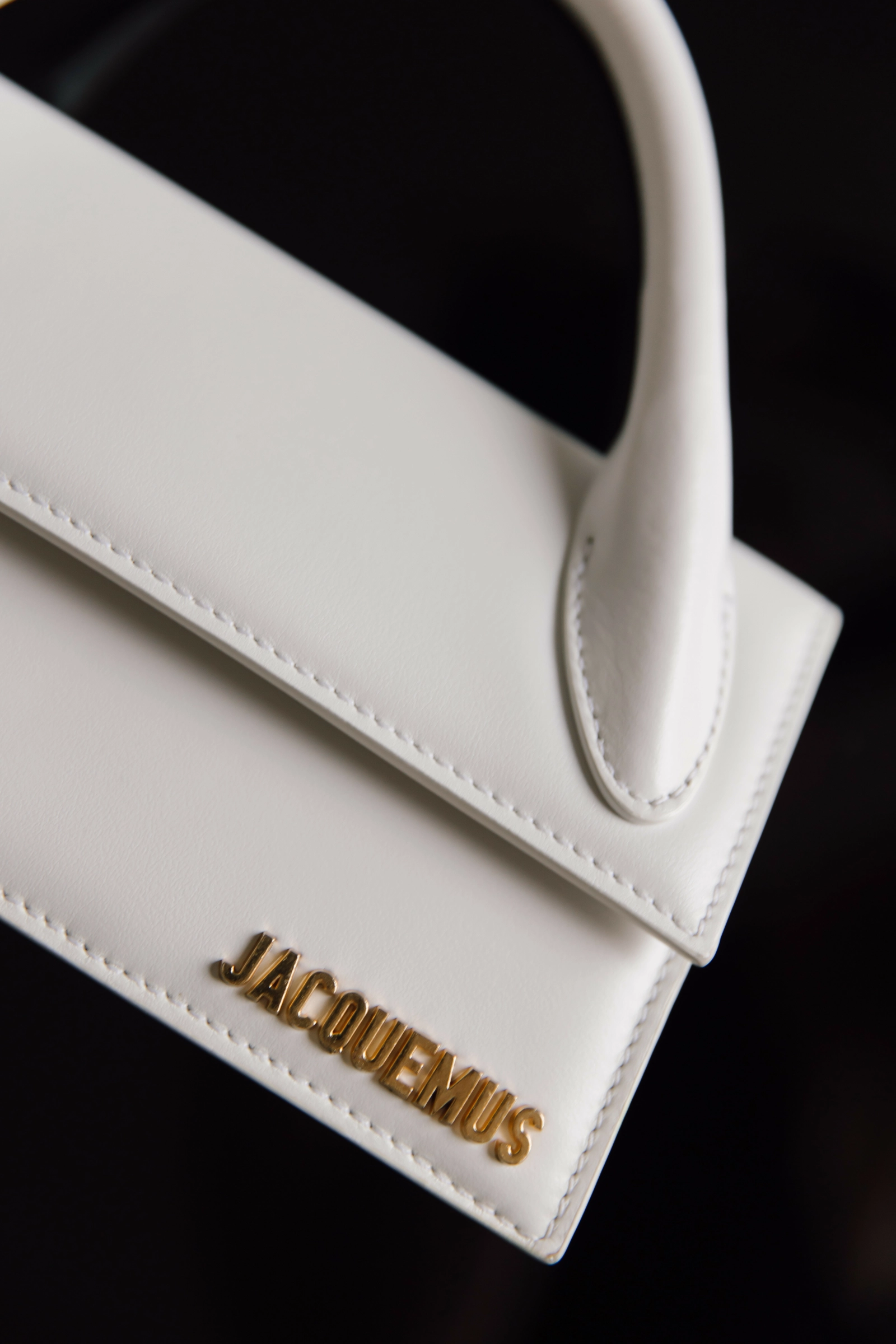 белая сумка jacquemus с золотыми буквами бренда крупным планом