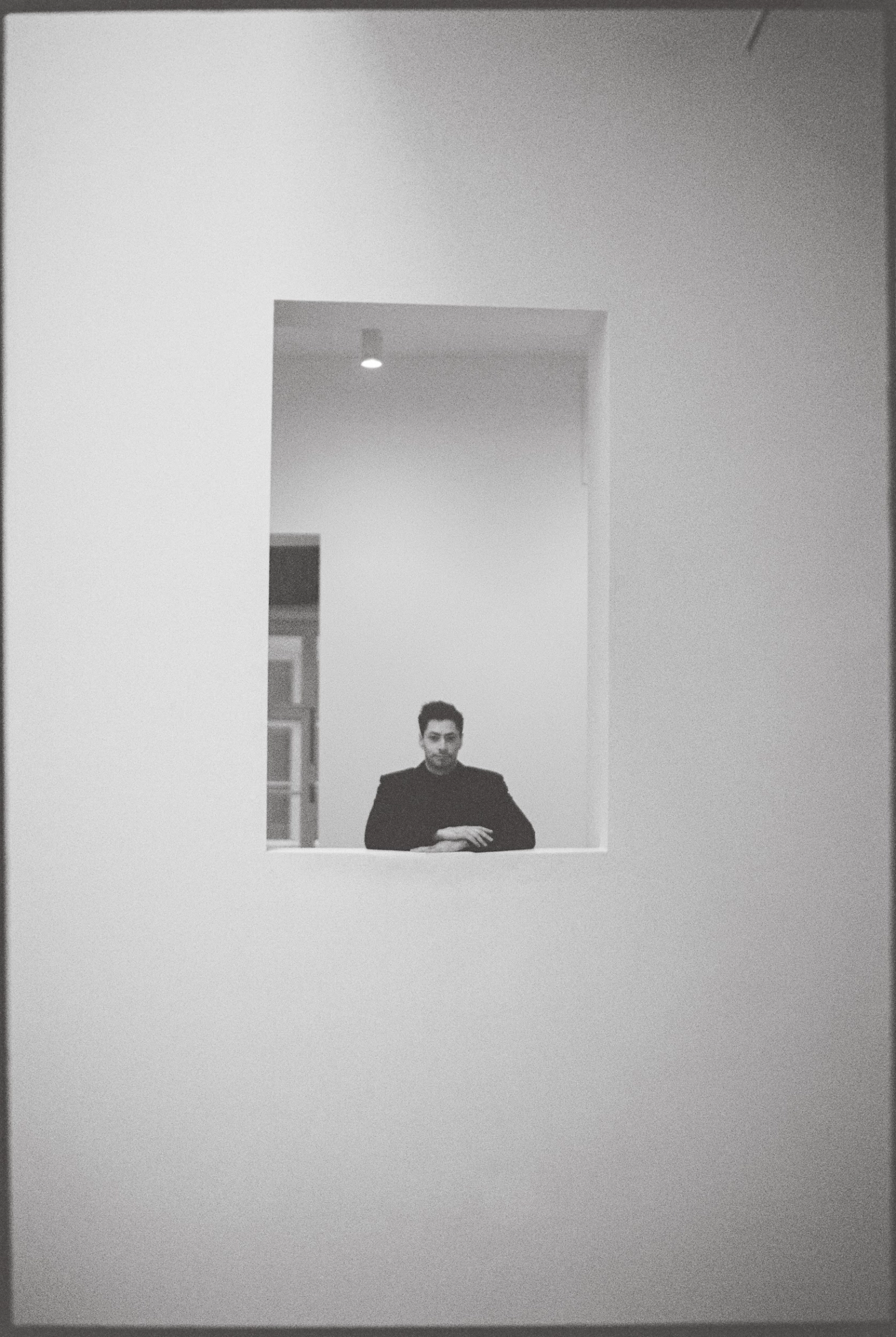 Ведущий в чёрной водолазке в оконном проёме светлого минималистичного интерьера