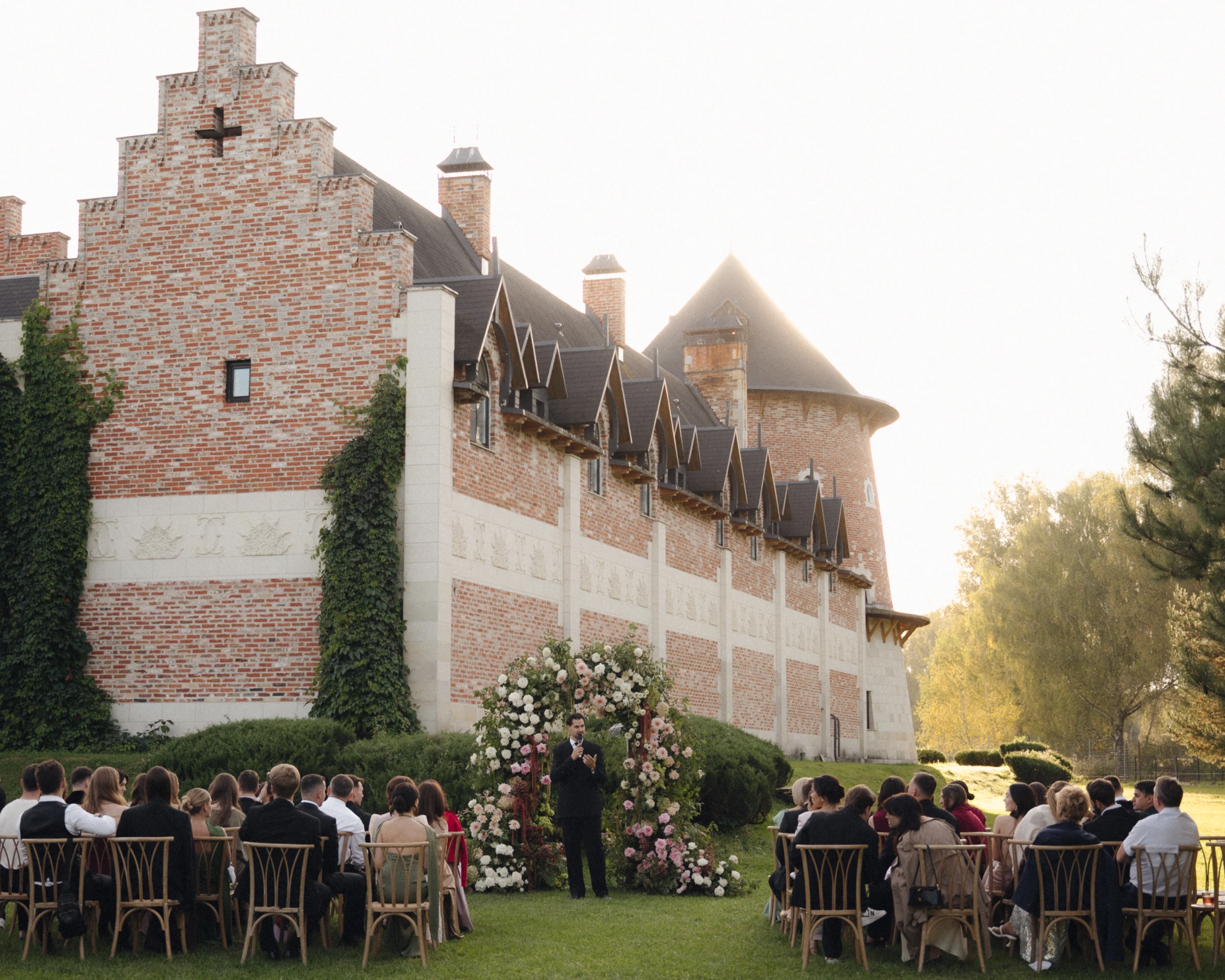 Выездная церемония у цветочной арки на фоне краснокирпичного замка