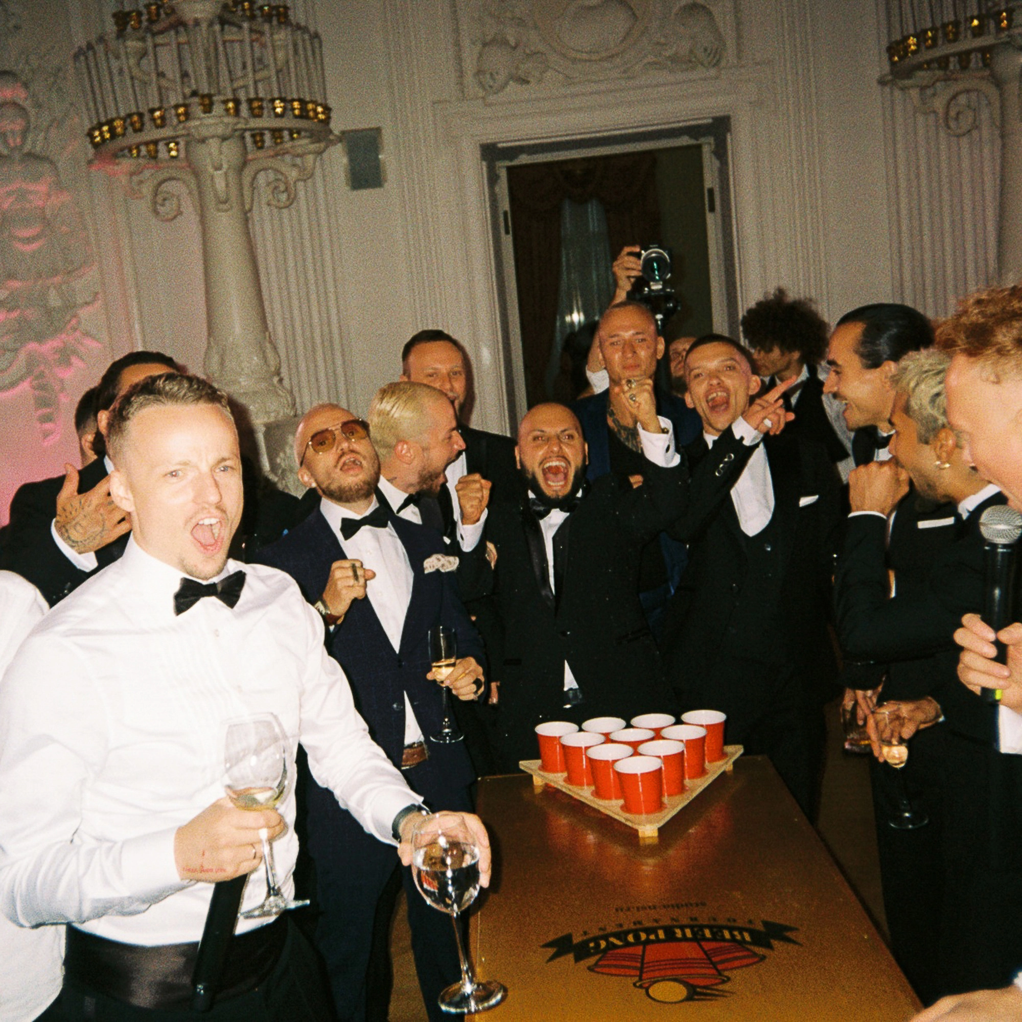 гости в смокингах играют в beer pong на свадебном afterparty