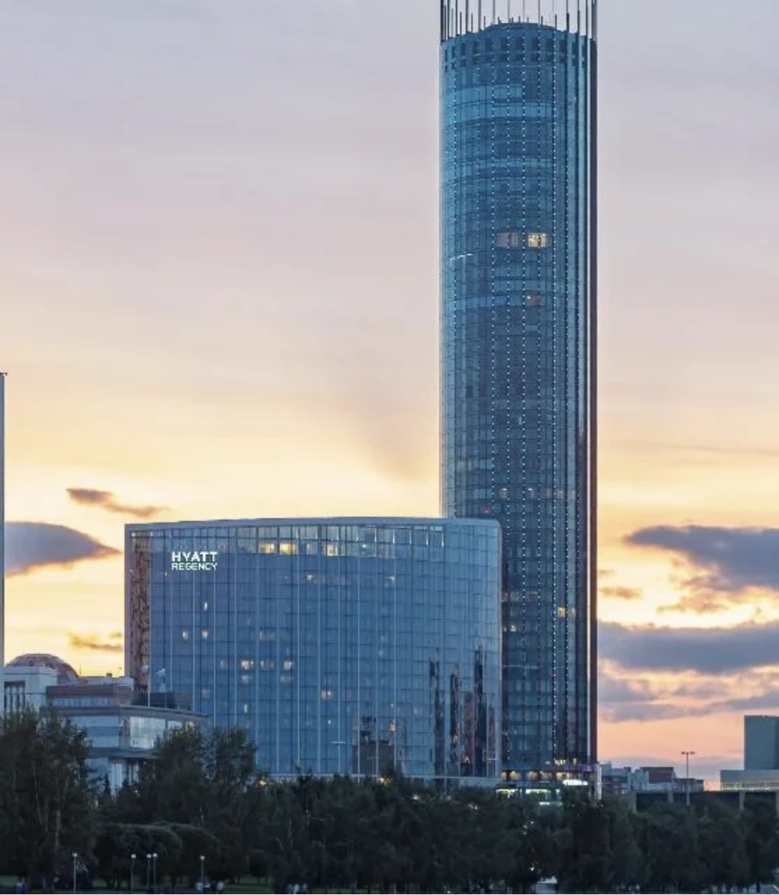 фасад отеля Hyatt Regency рядом с небоскрёбом на закате