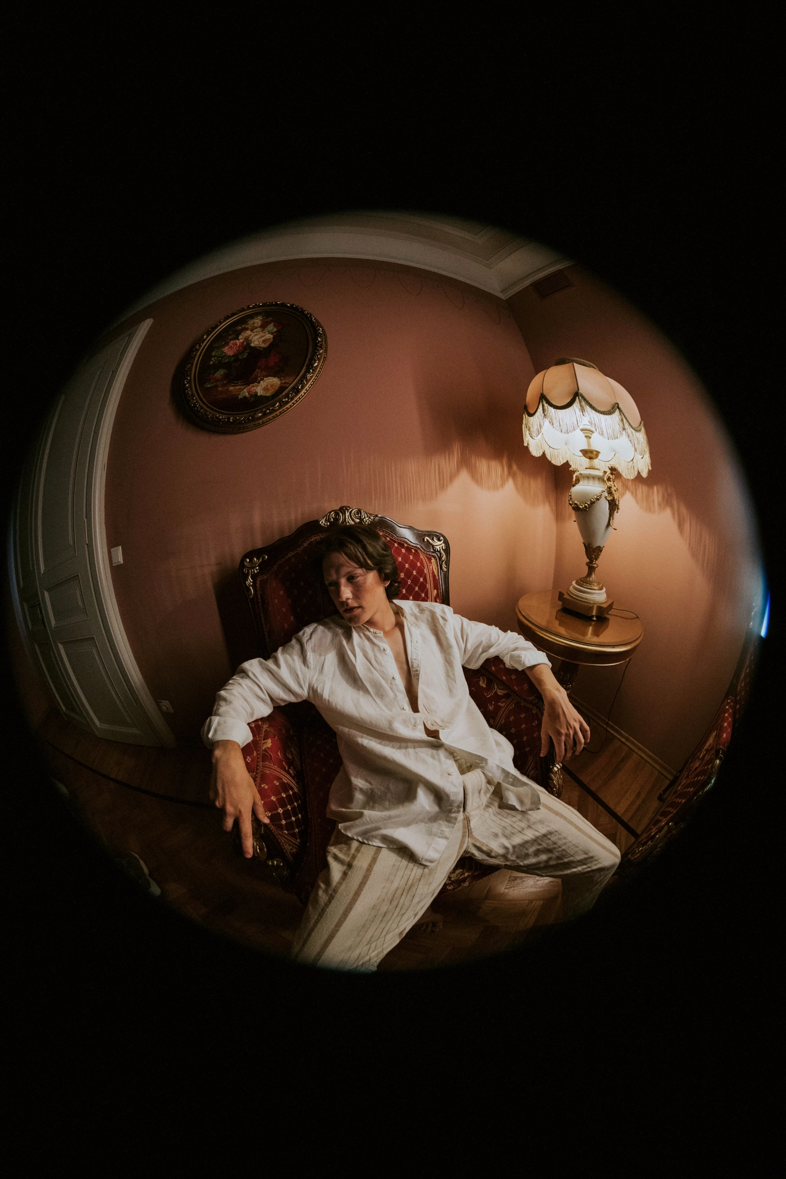 Жених в винтажном кресле розовой комнаты, портрет через круглый fisheye-объектив
