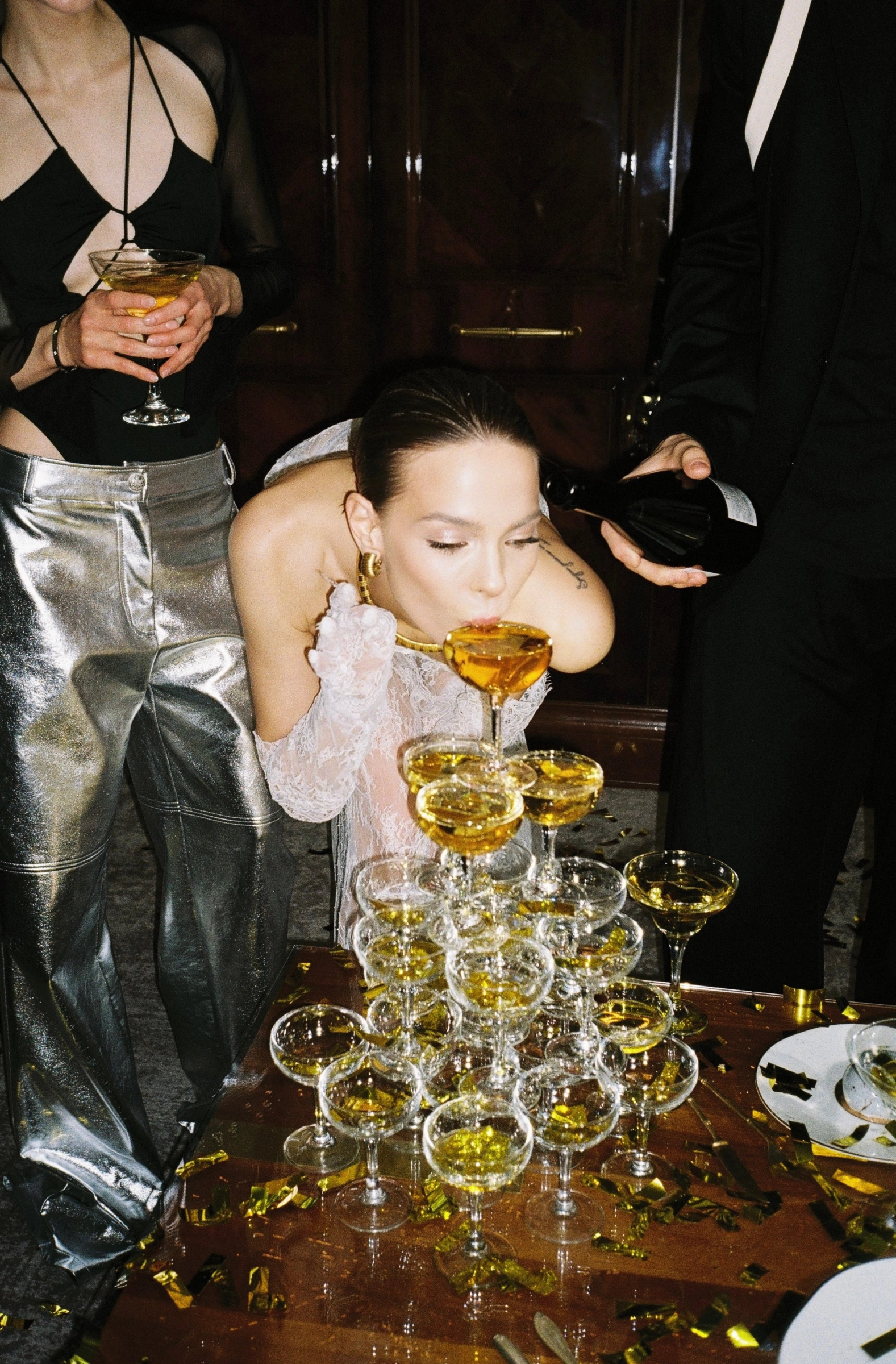 Невеста пьёт шампанское из башни бокалов на свадебном afterparty