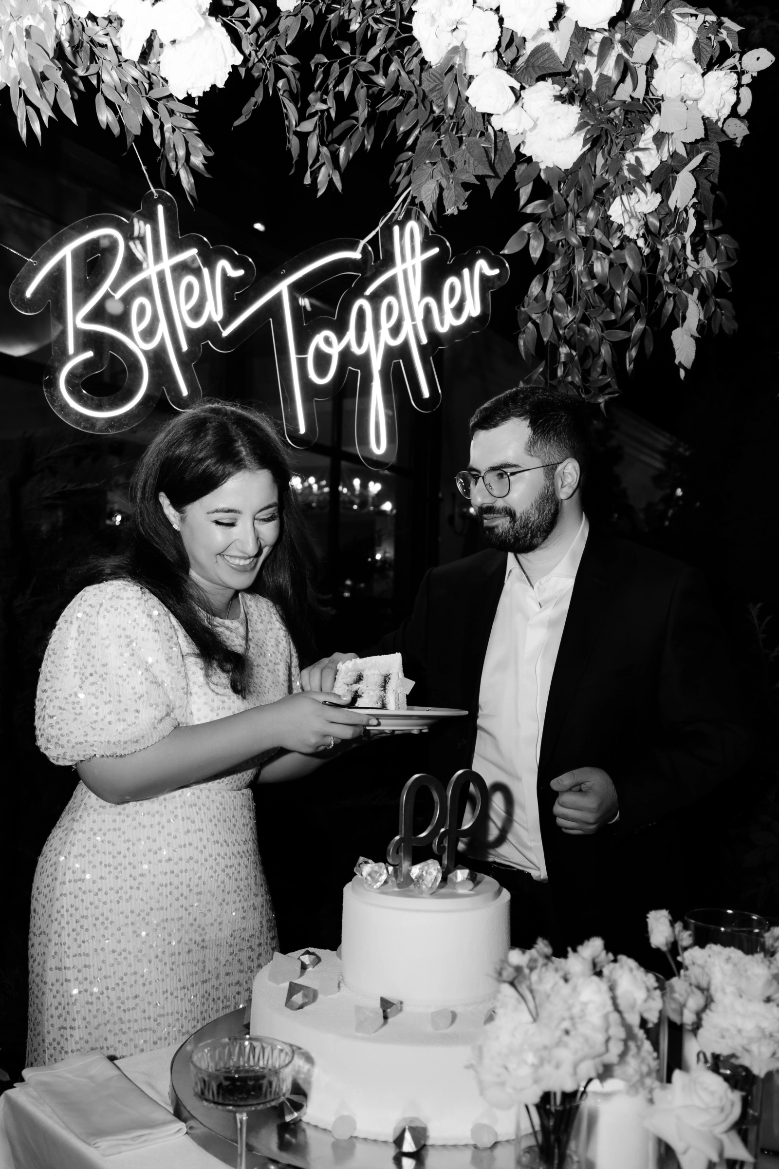 Жених и невеста разрезают торт под неоновой вывеской Better Together