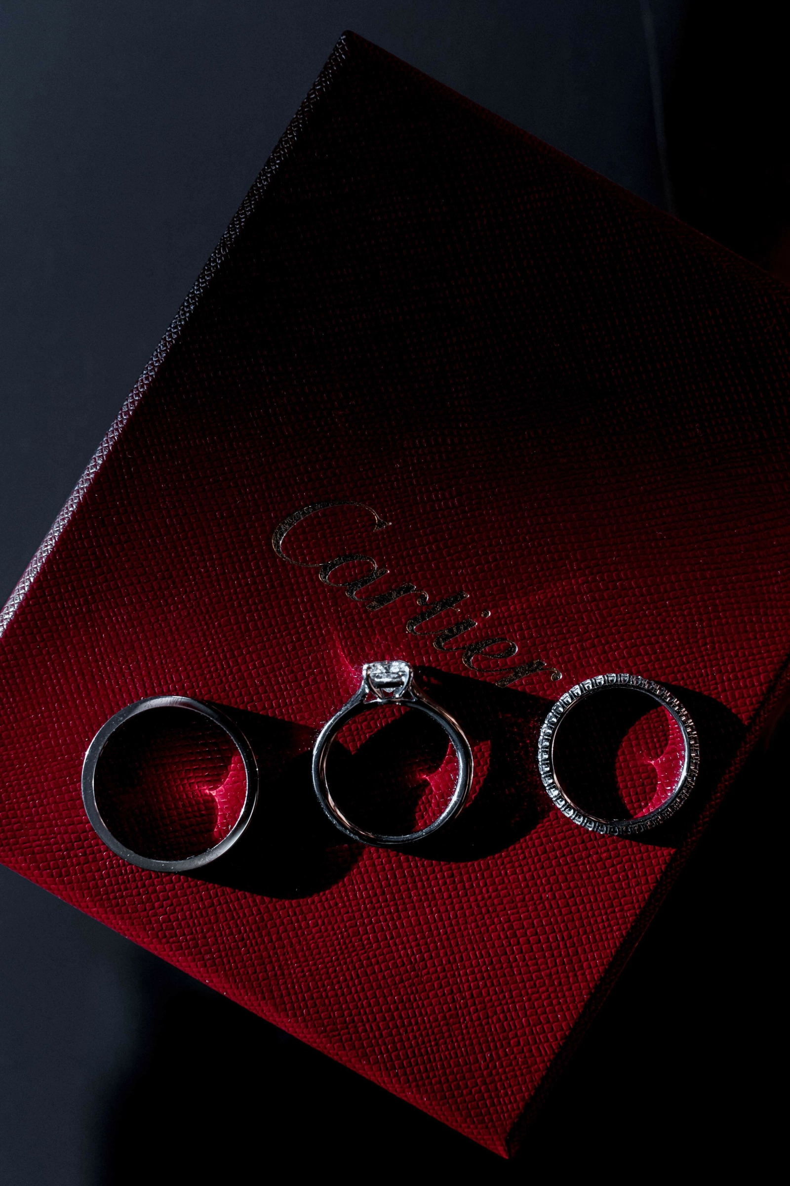 Три обручальных кольца на бордовой коробке Cartier крупным планом