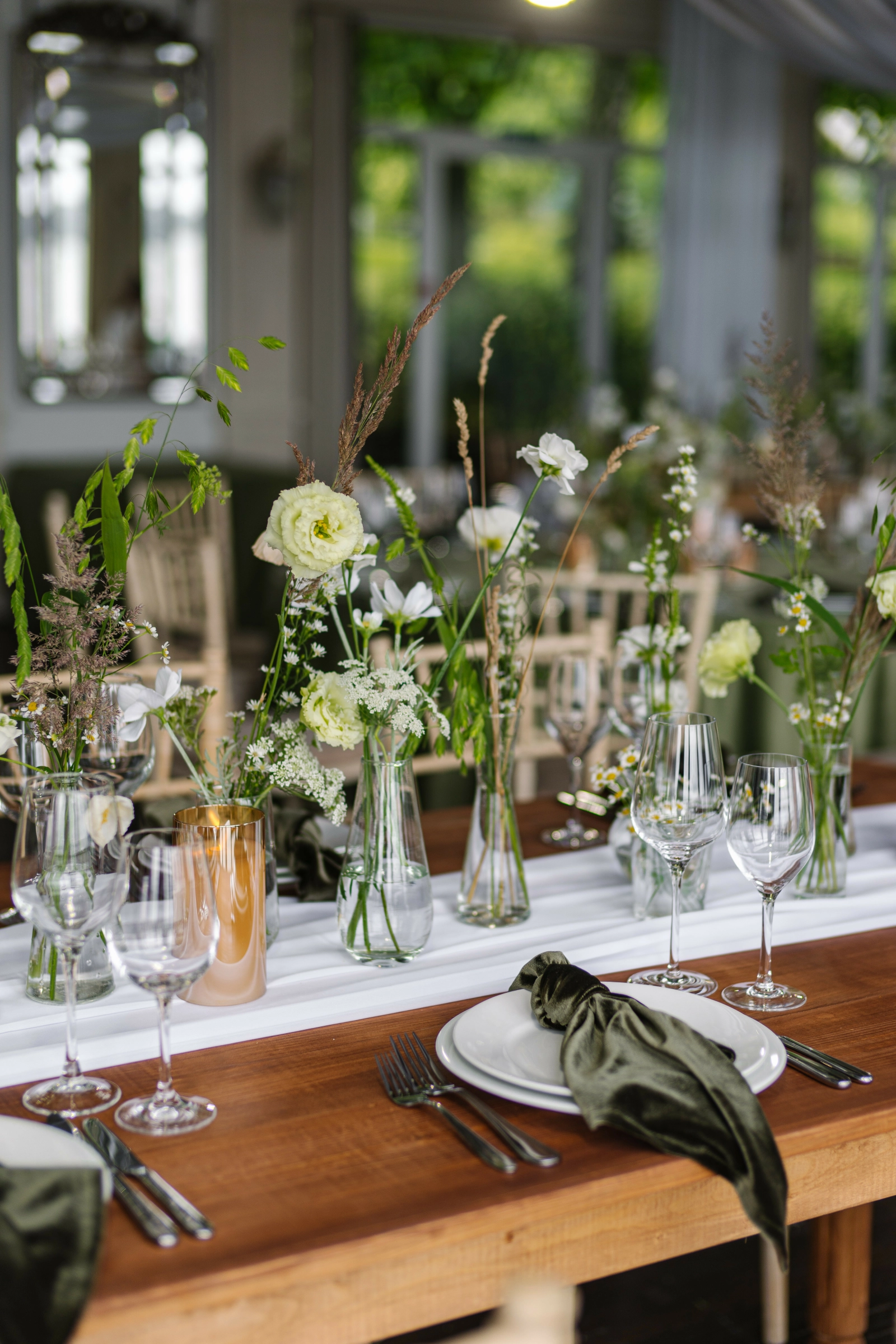 Банкетный стол с вазами полевых цветов и колосков у стеклянной стены