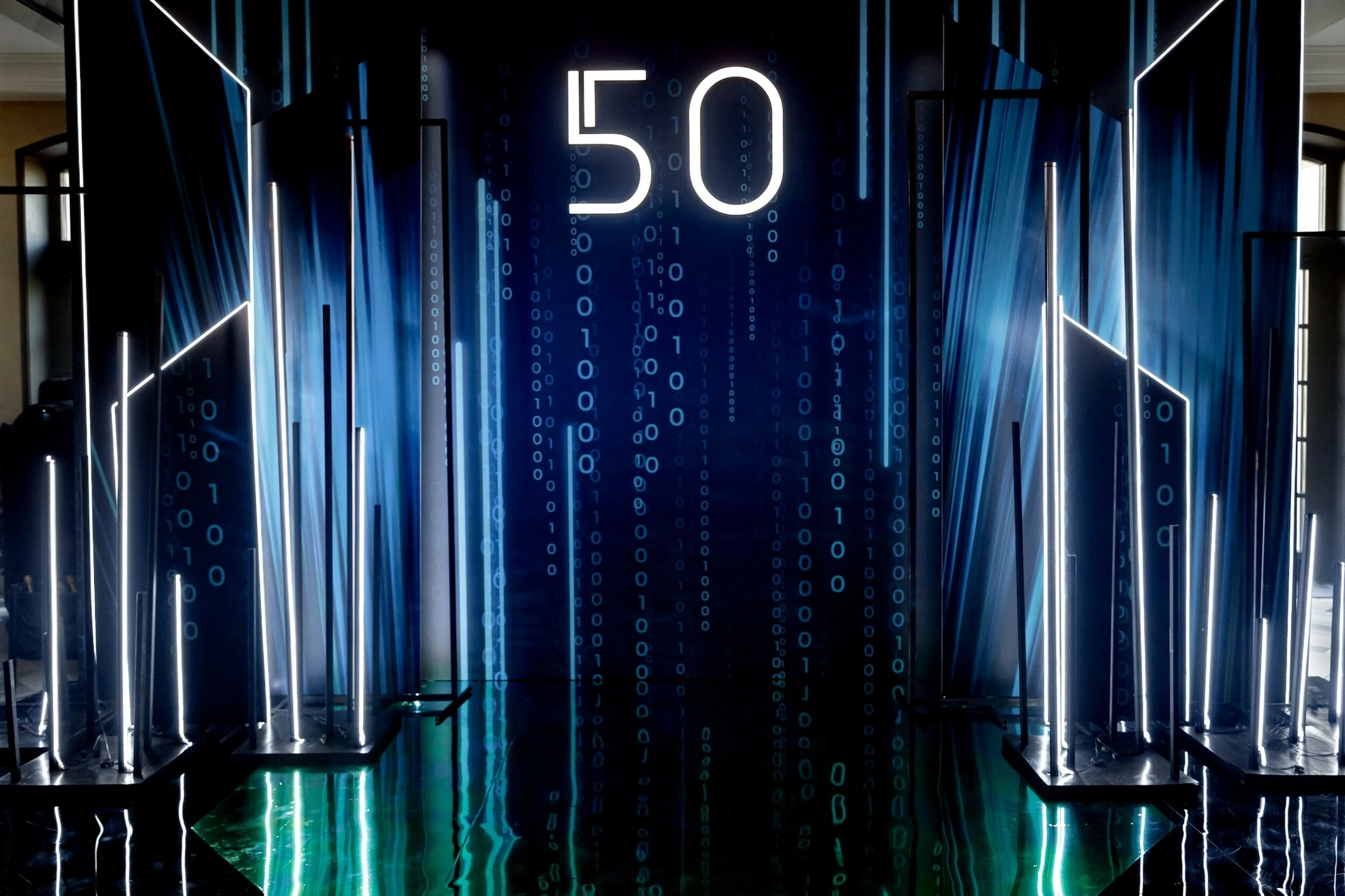 неоновое оформление юбилея 50 на фоне бинарного кода в банкетном зале
