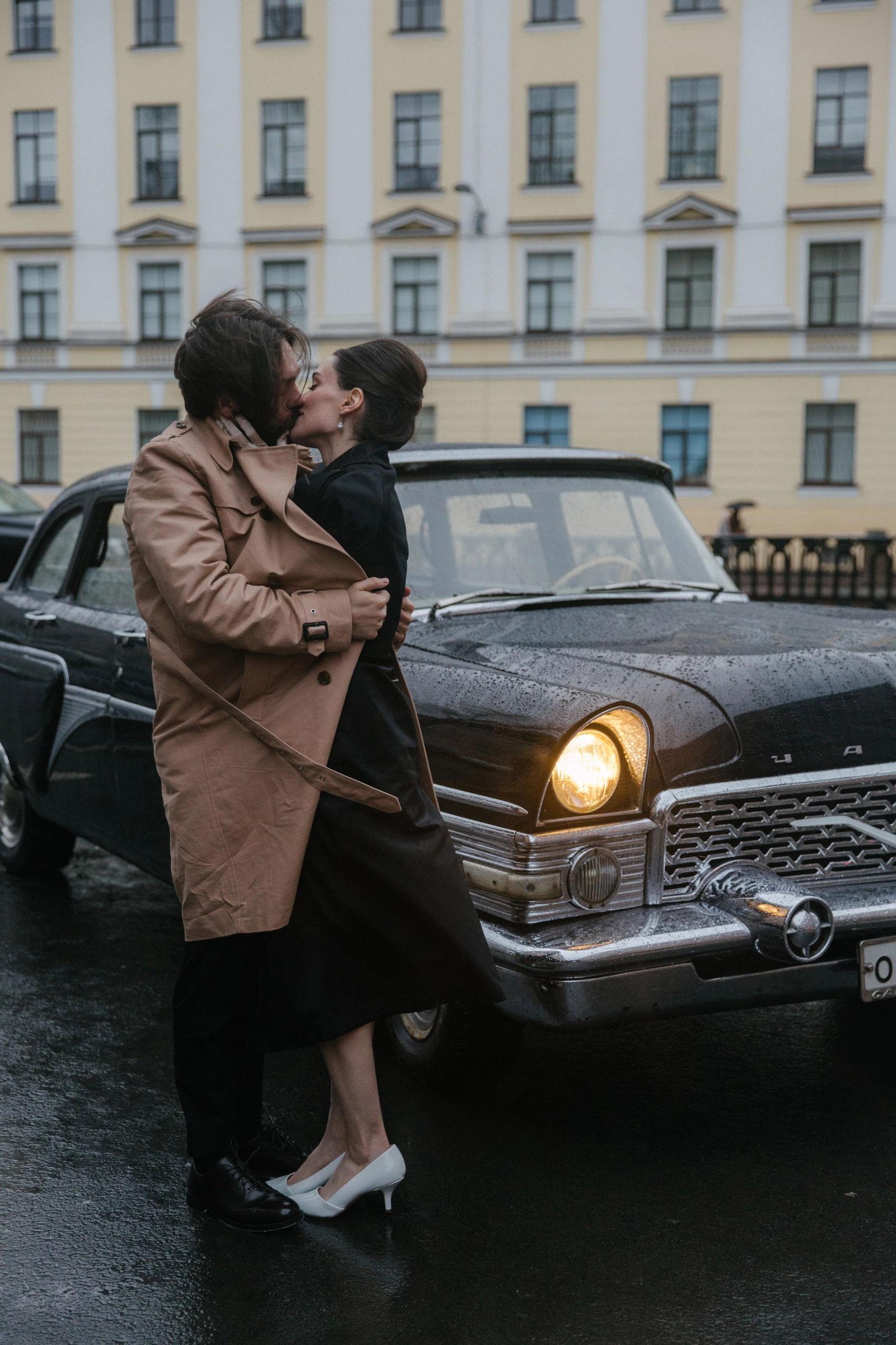 поцелуй пары под дождём у ретроавтомобиля с горящей фарой