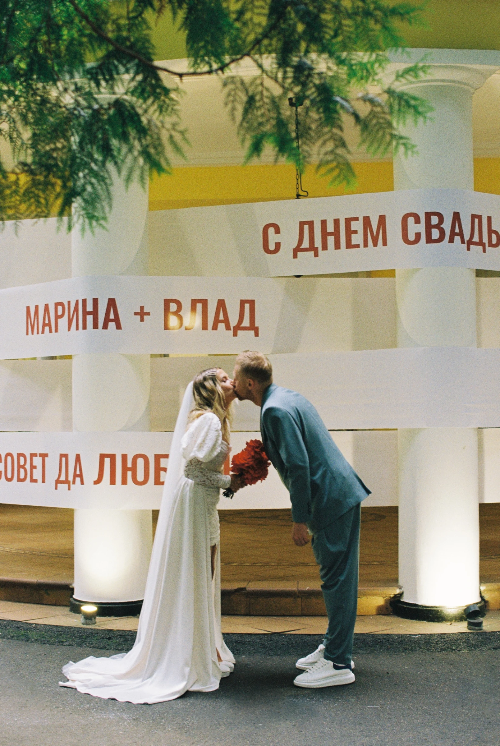 Свадебная фотозона с текстильными растяжками-поздравлениями у белых колонн