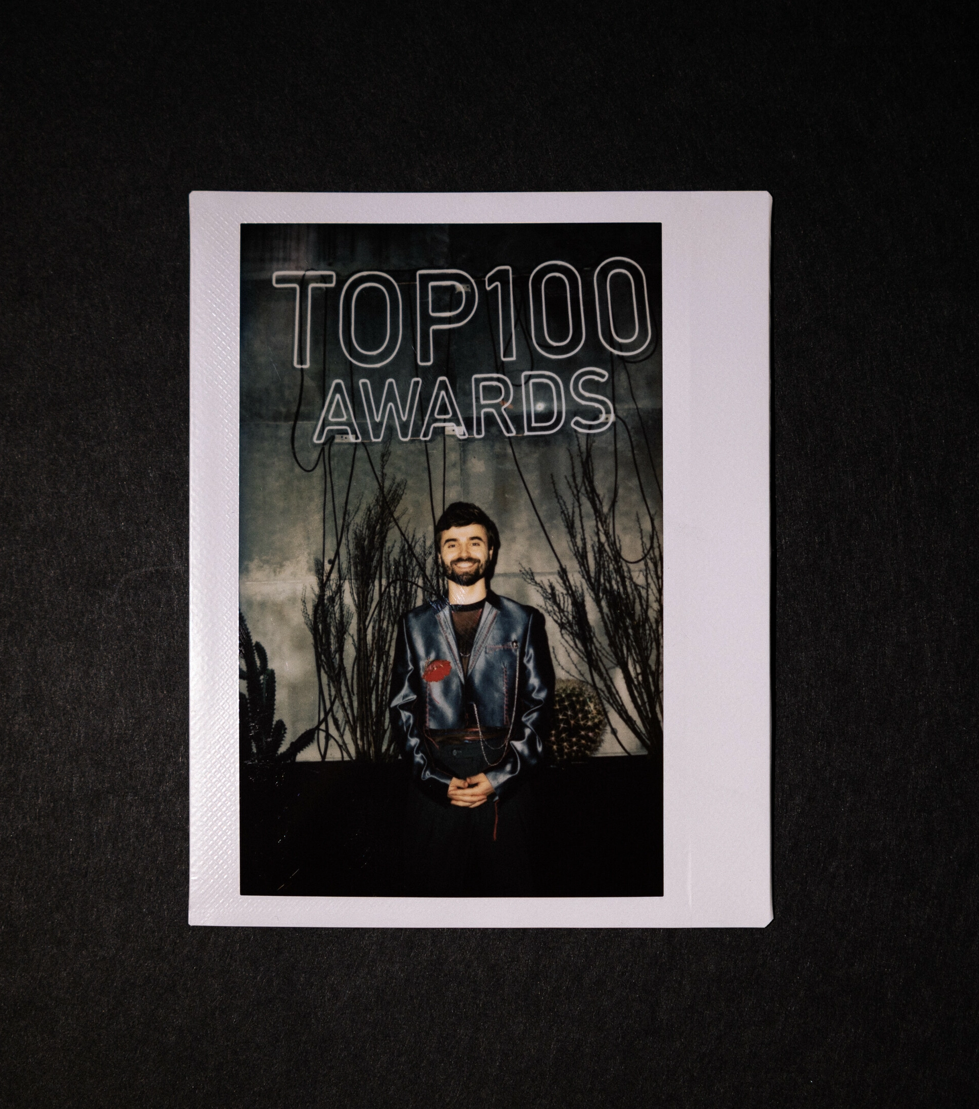 ведущий у неоновой вывески премии TOP100 Awards в стиле полароида
