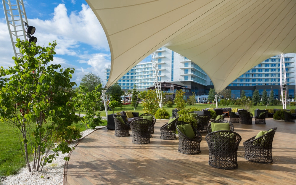 Modern rattan lounge furniture under cream canopy at seaside resort