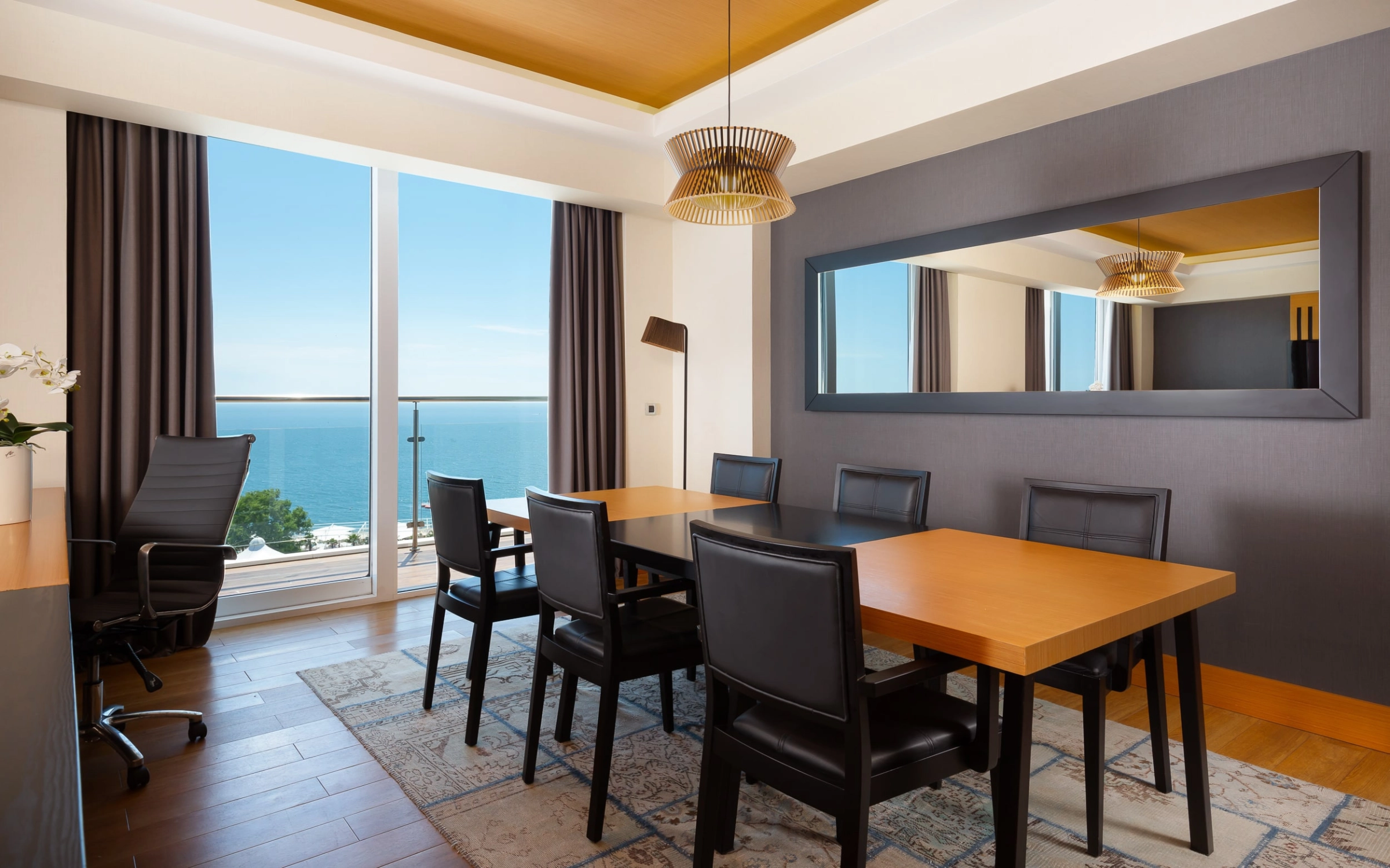 Executive suite with sea view seating area and golden pendant lighting