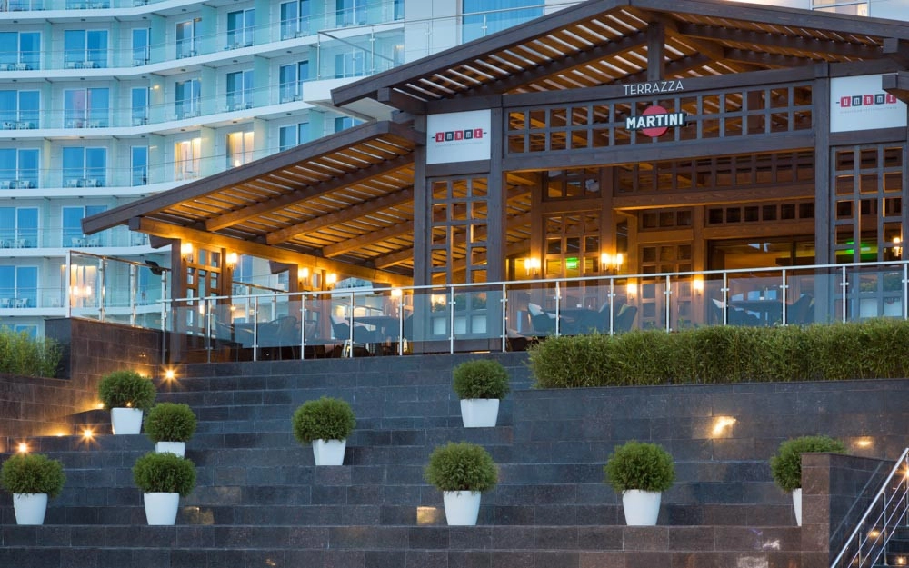 Illuminated wooden pergola terrace with landscaped stone seating area