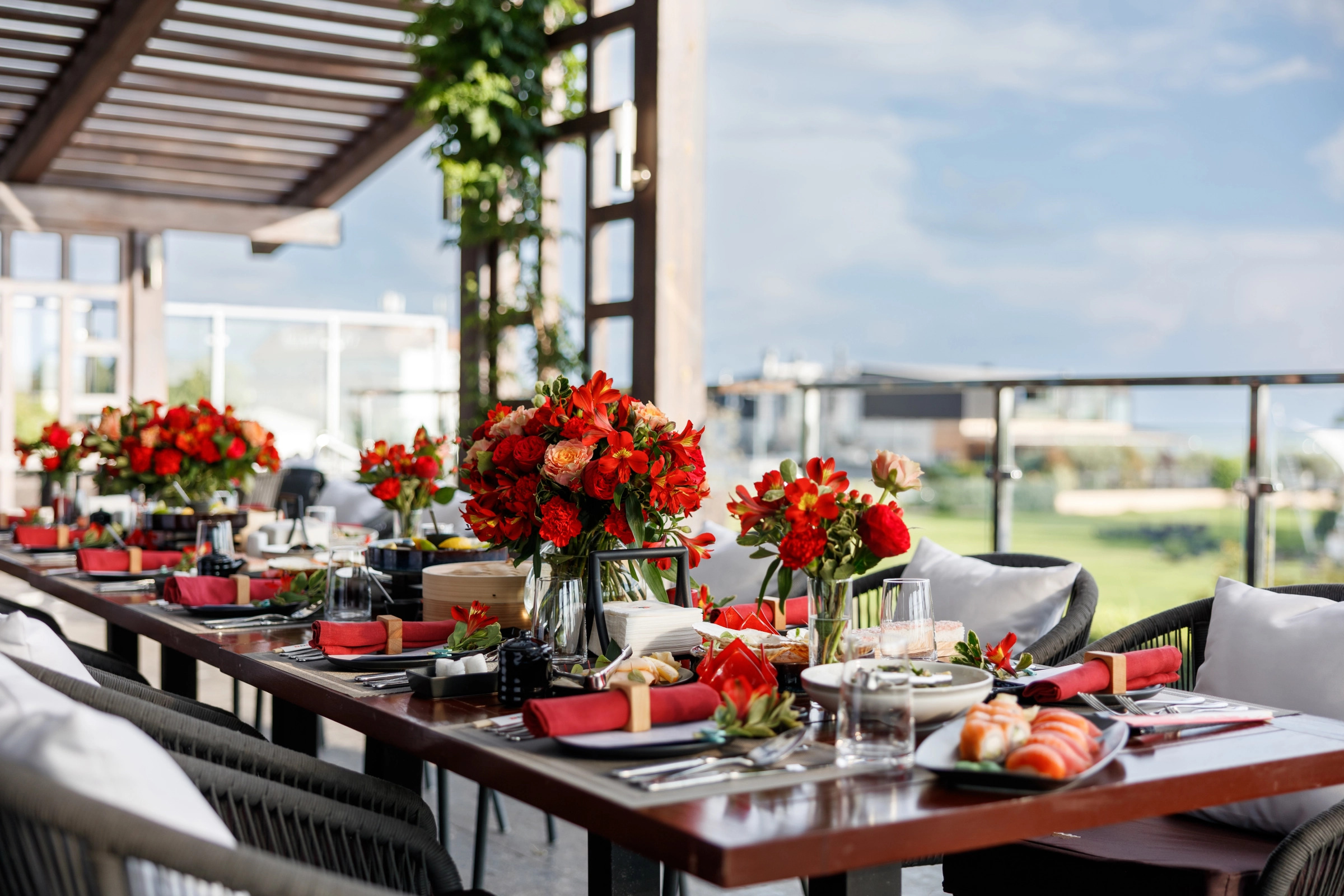 Wedding reception table red flowers white linens outdoor terrace setting