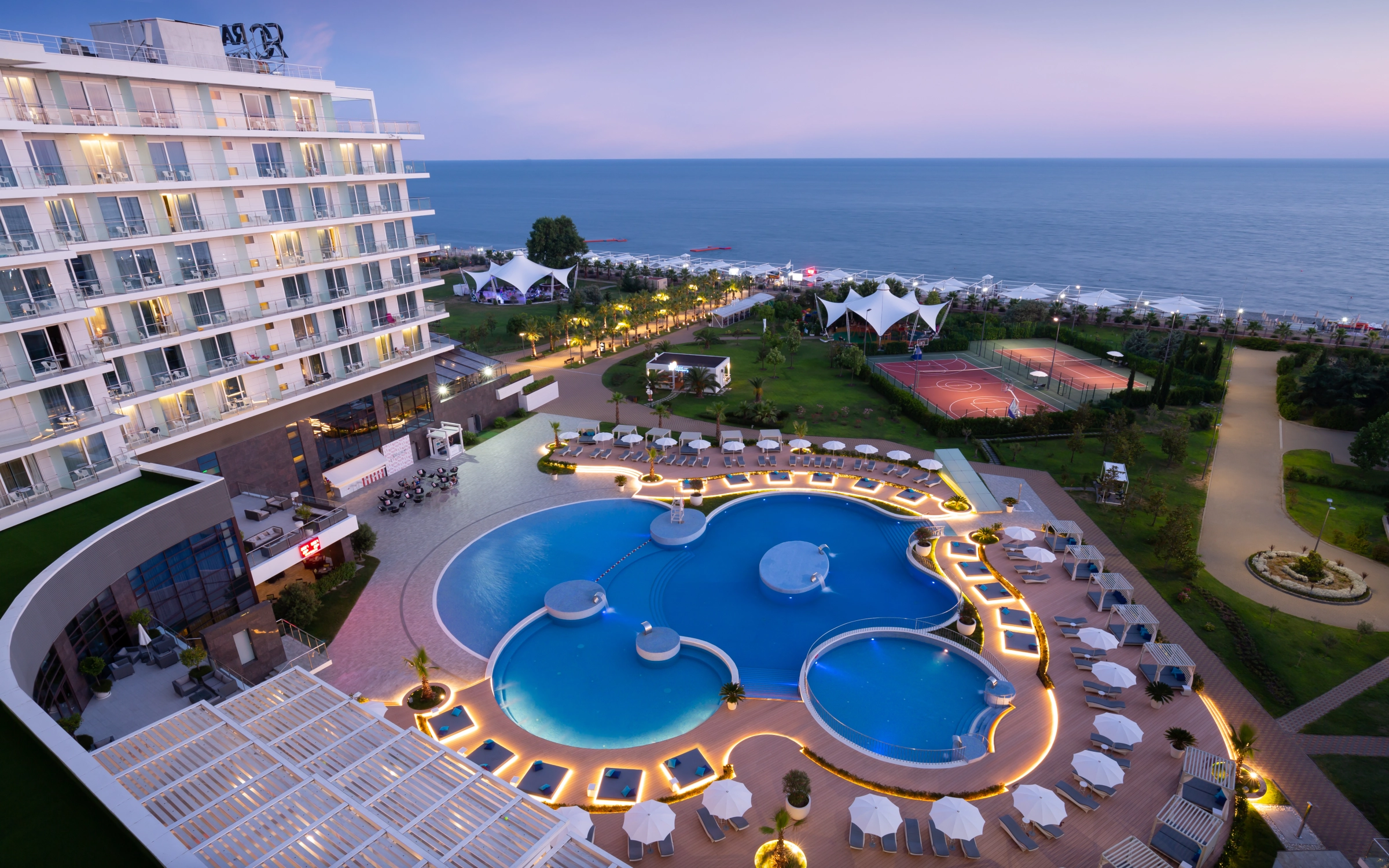 Resort pool complex with multiple swimming pools illuminated at dusk