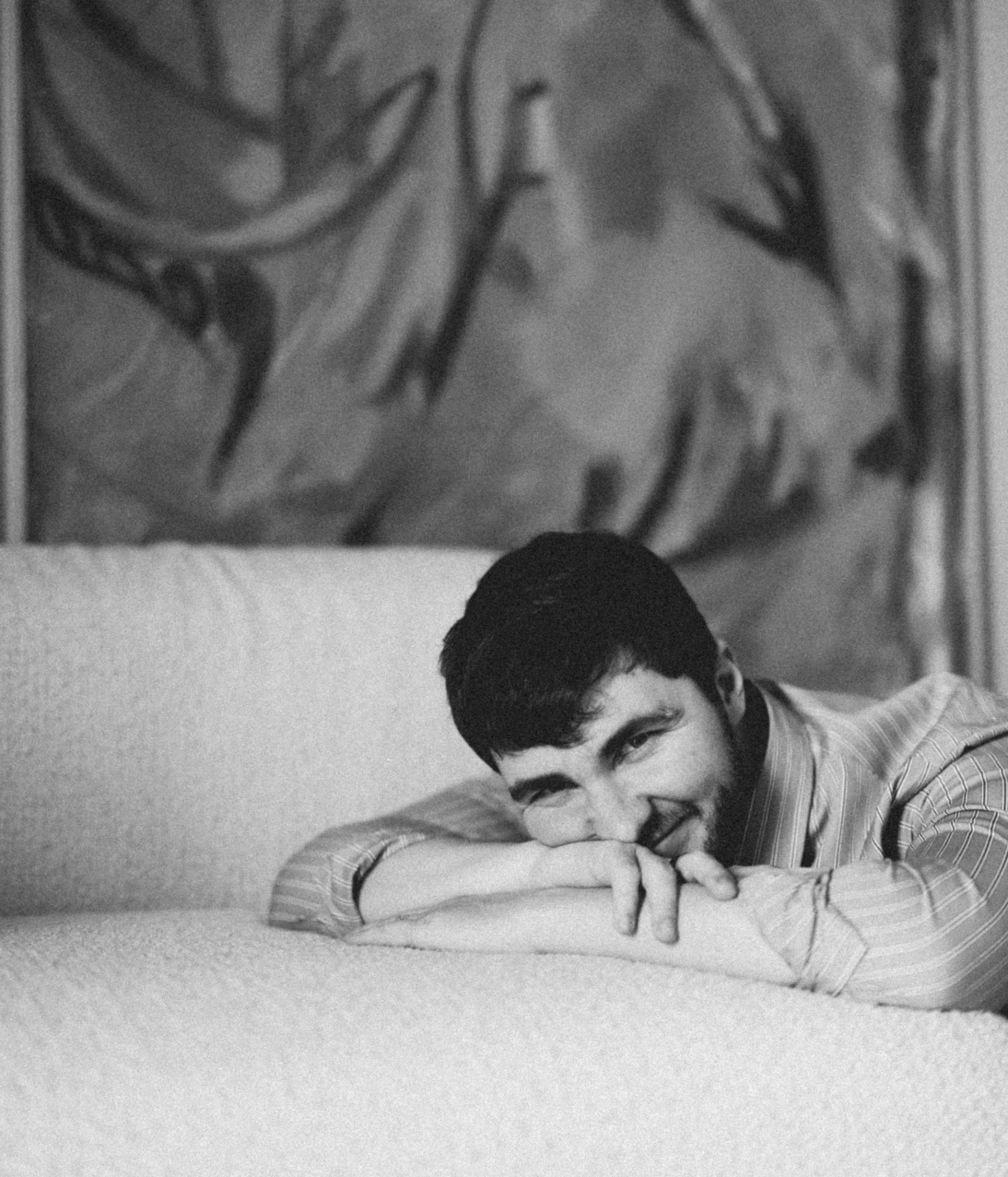 мужчина лежит на светлом диване подперев голову руками