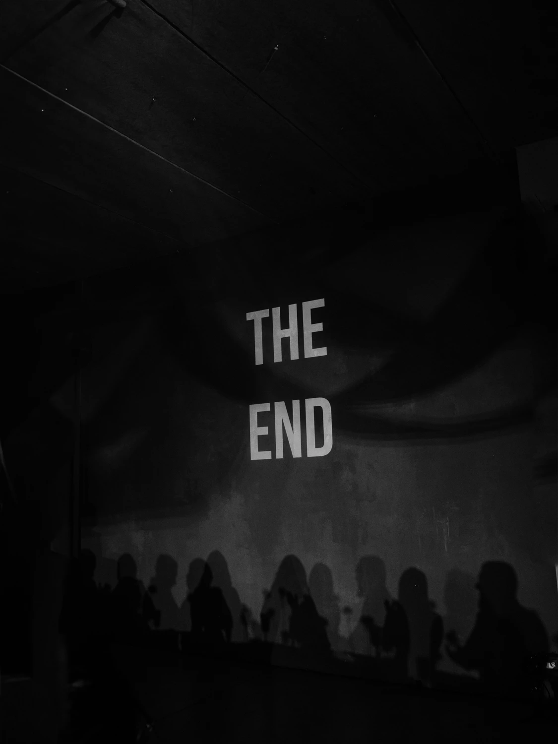надпись the end проецируется над силуэтами гостей на вечеринке