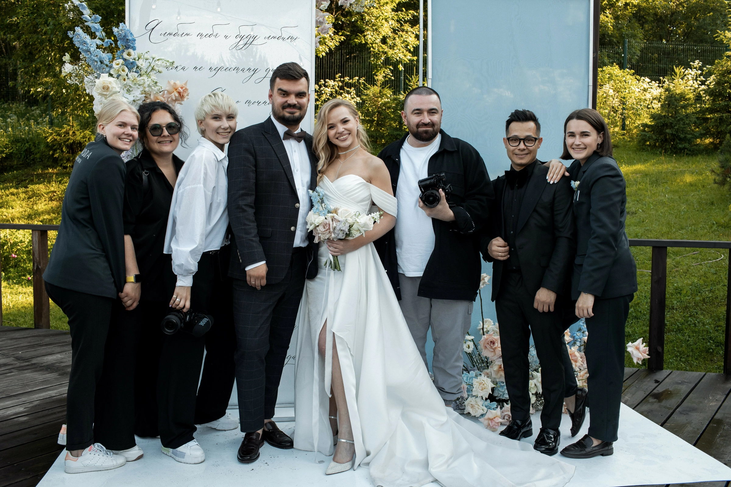 молодожёны с фотографом у флористической арки на улице