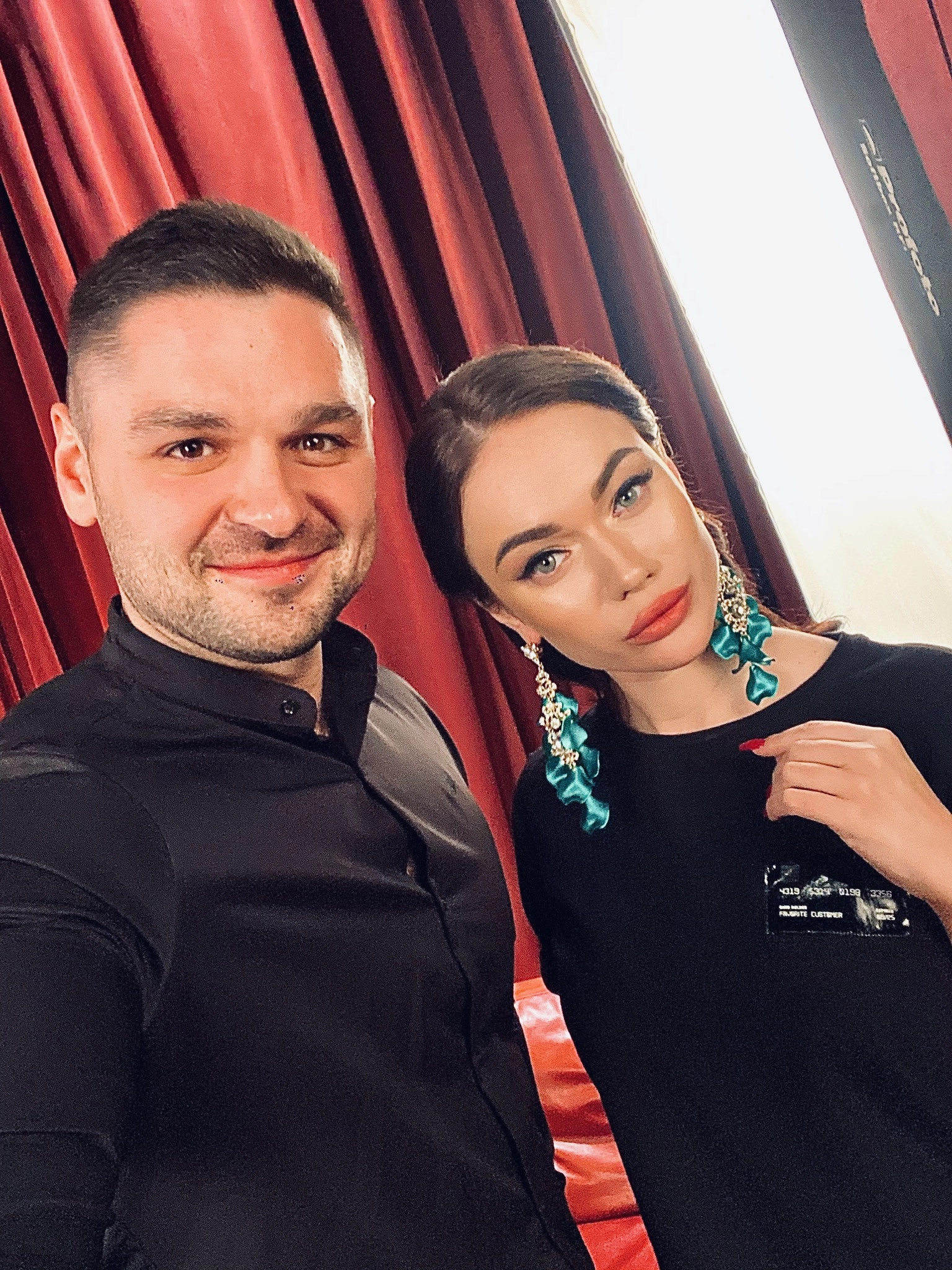 ведущий свадьбы позирует с гостьей на фоне бордовых портьер