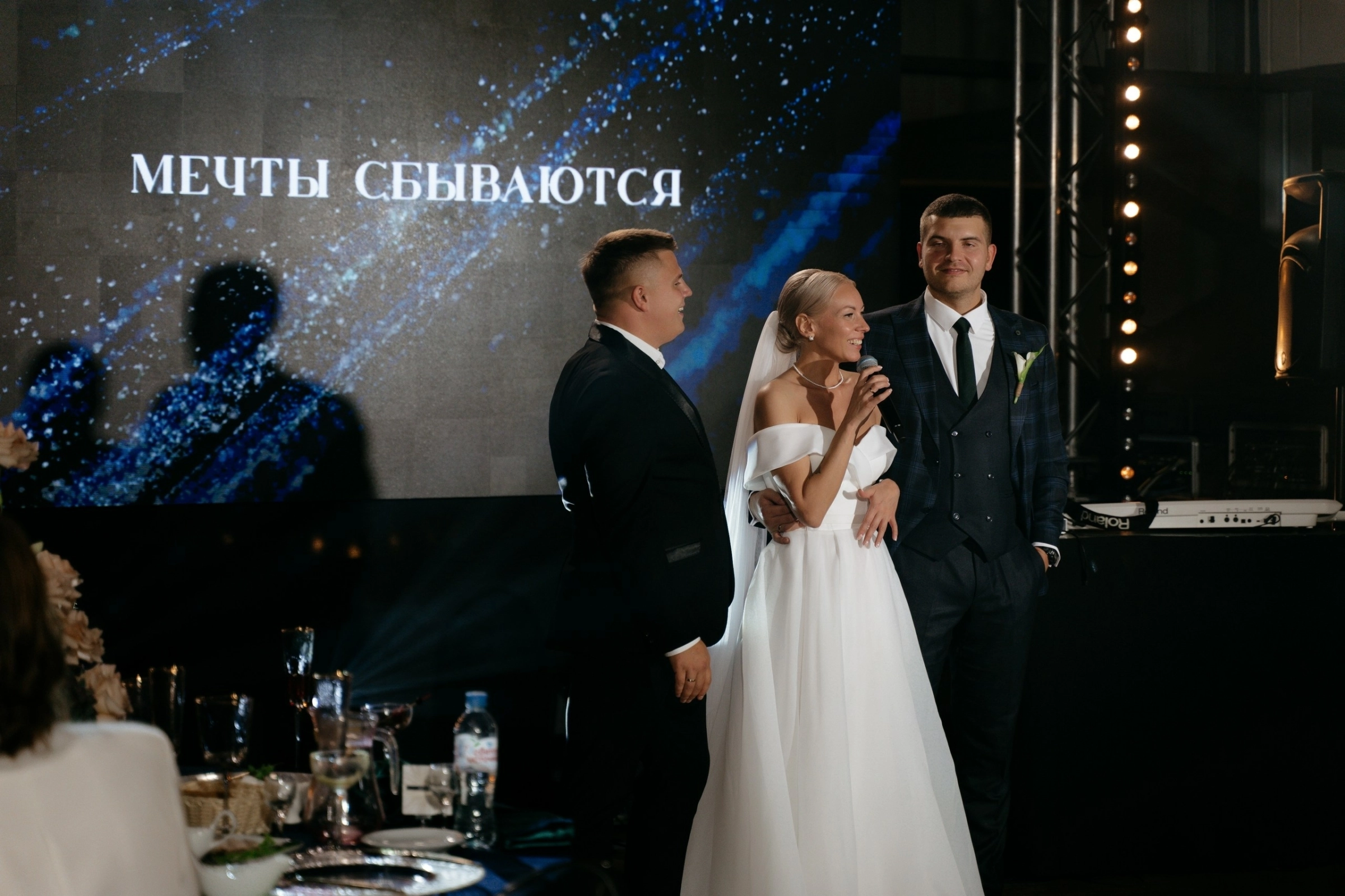 Невеста произносит речь в микрофон рядом с ведущим на сцене