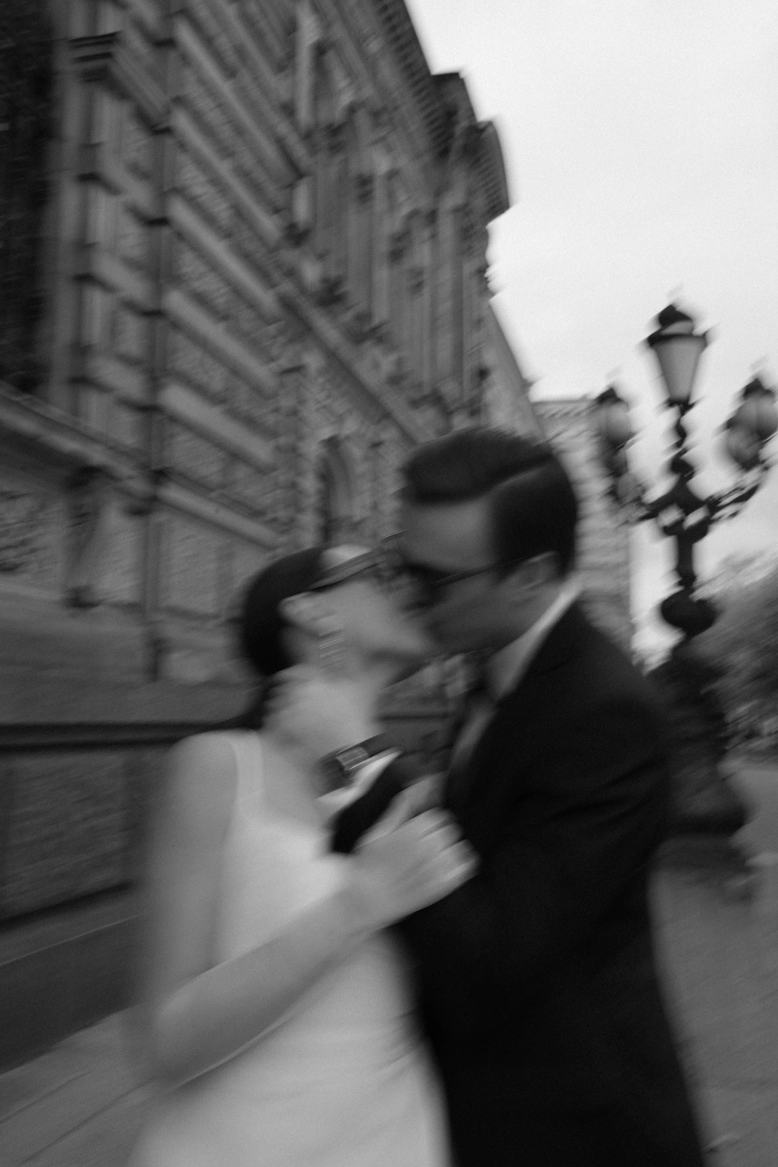 молодожёны целуются на улице у старинного здания с фонарём, чёрно-белое фото