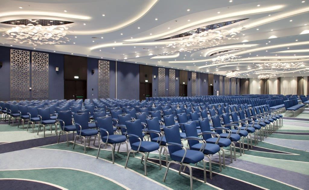 банкетный зал с волнистым подсвеченным потолком и рядами синих кресел