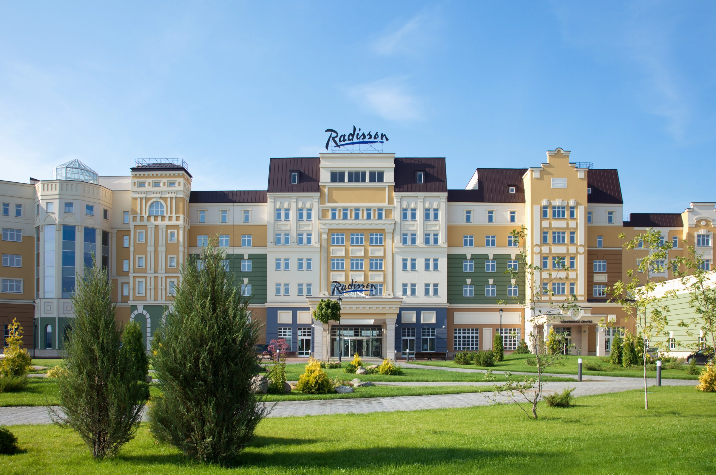 фасад отеля Radisson с башенками и зелёным газоном перед входом