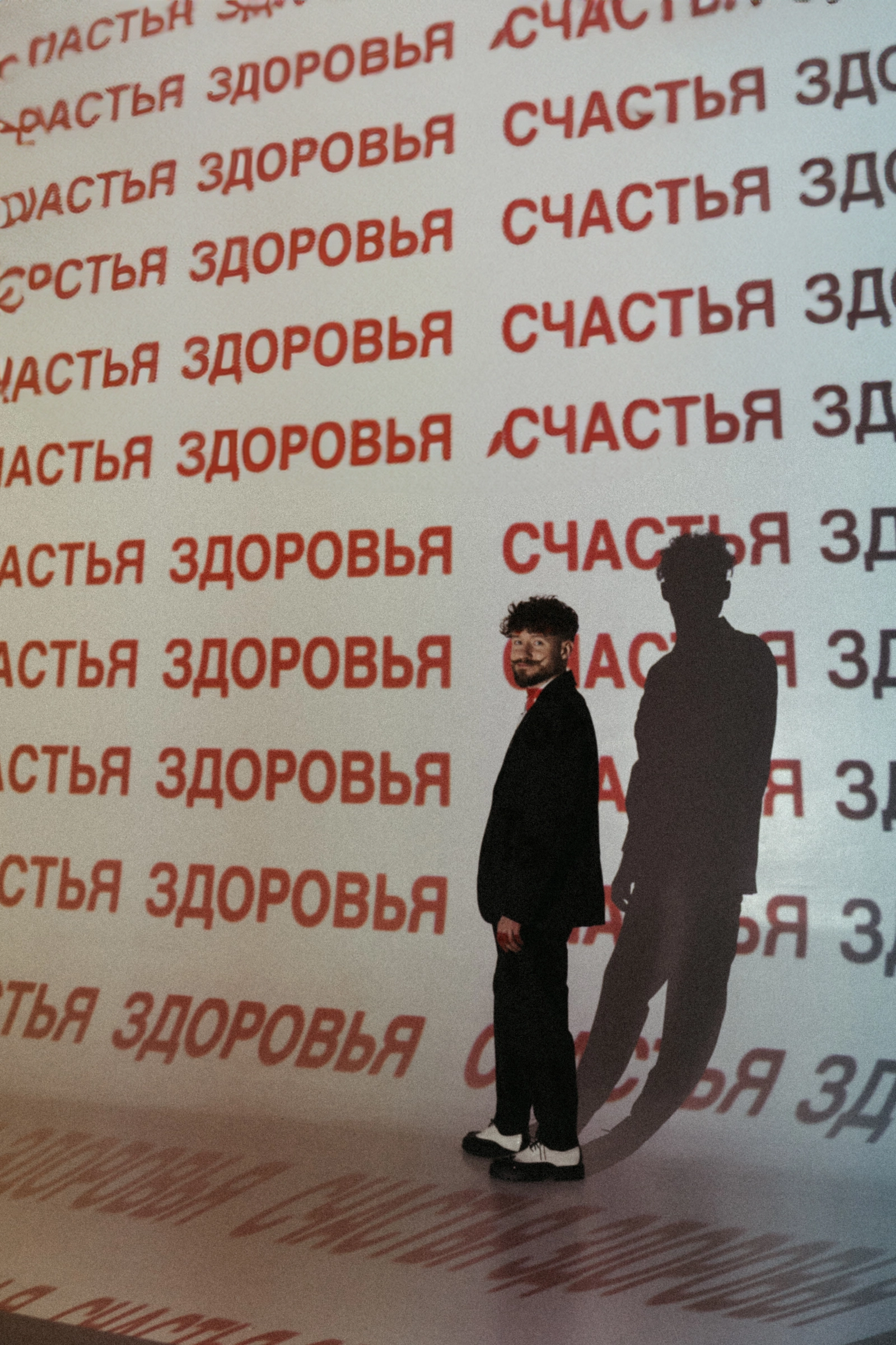 ведущий у фотостены с надписью и собственной тенью на фоне
