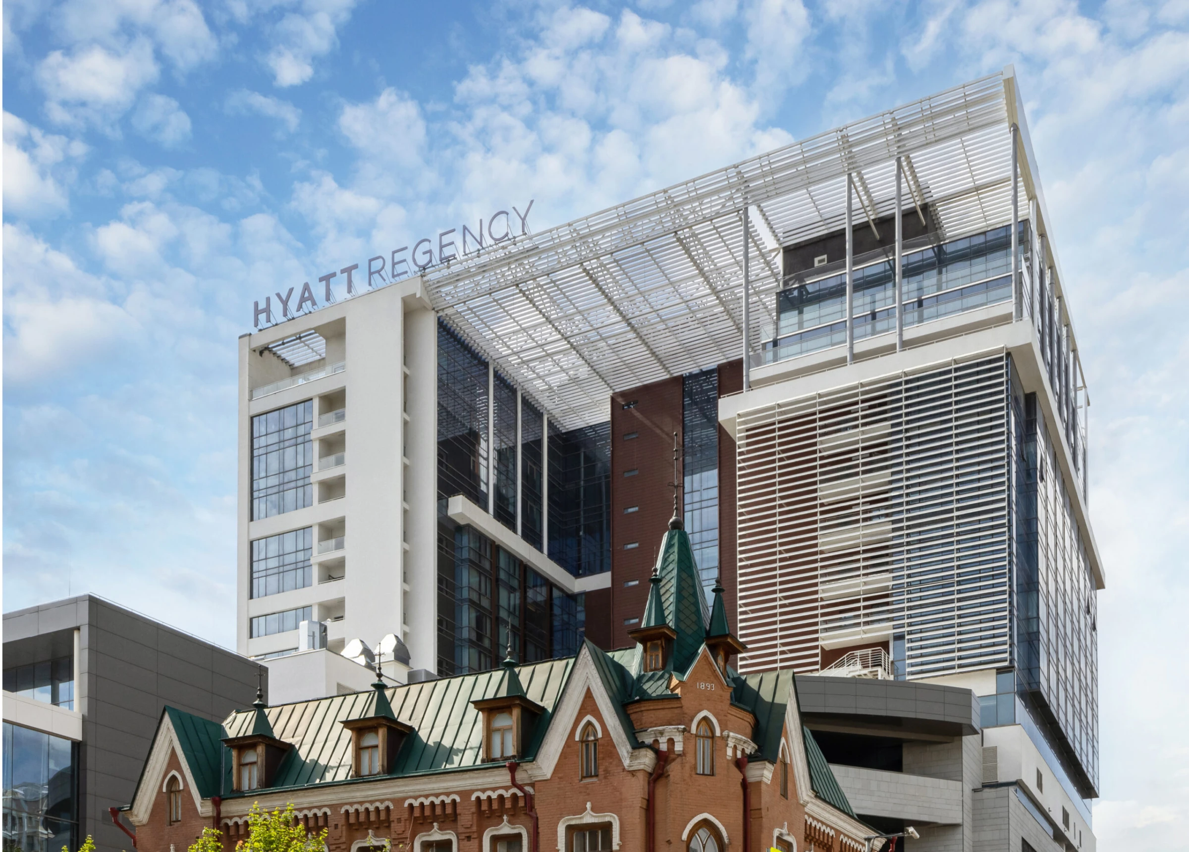 фасад высотного здания отеля с вывеской Hyatt Regency на фоне неба