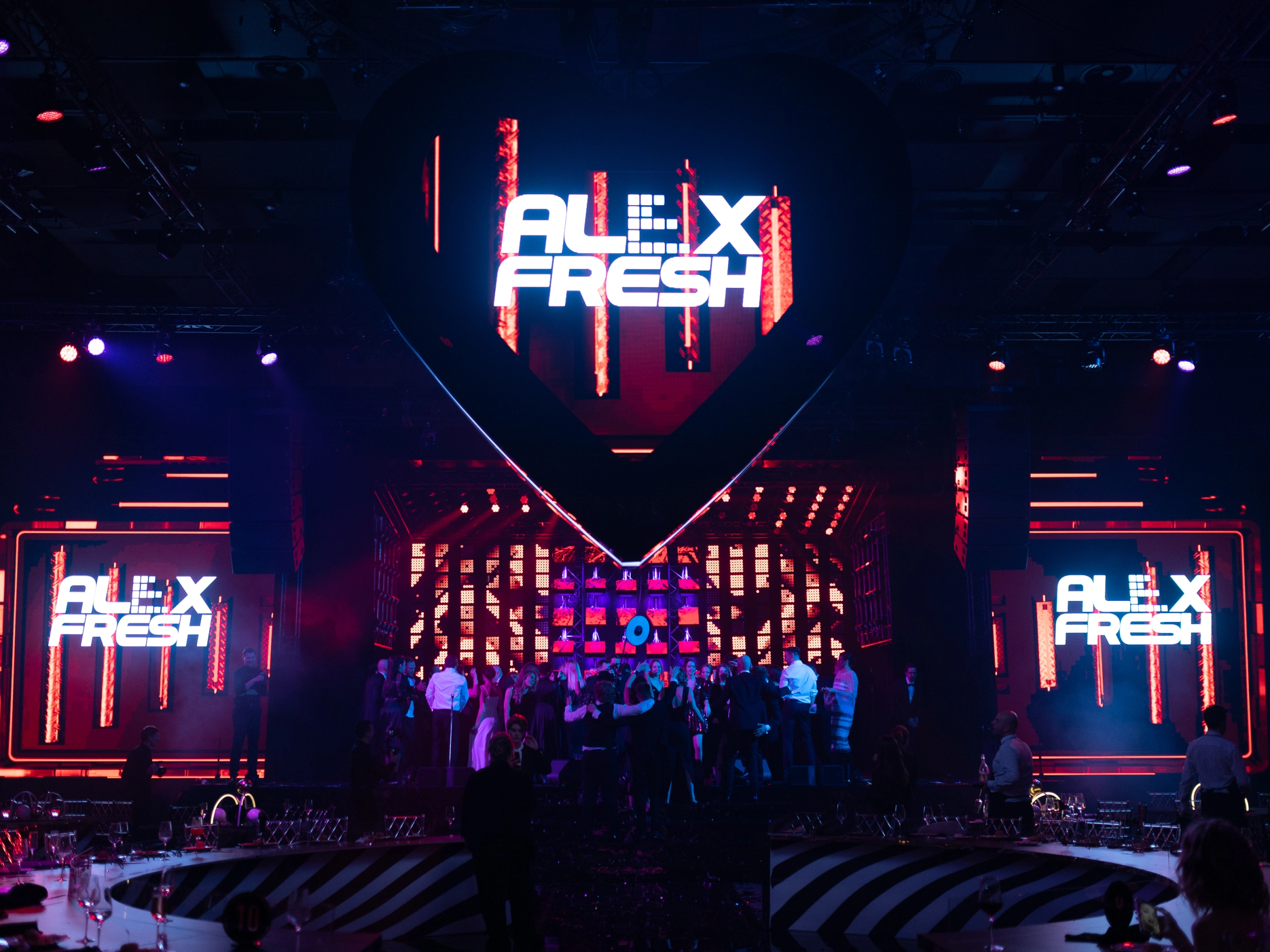 Неоновая вывеска Alex Fresh на сцене банкетного зала с гостями