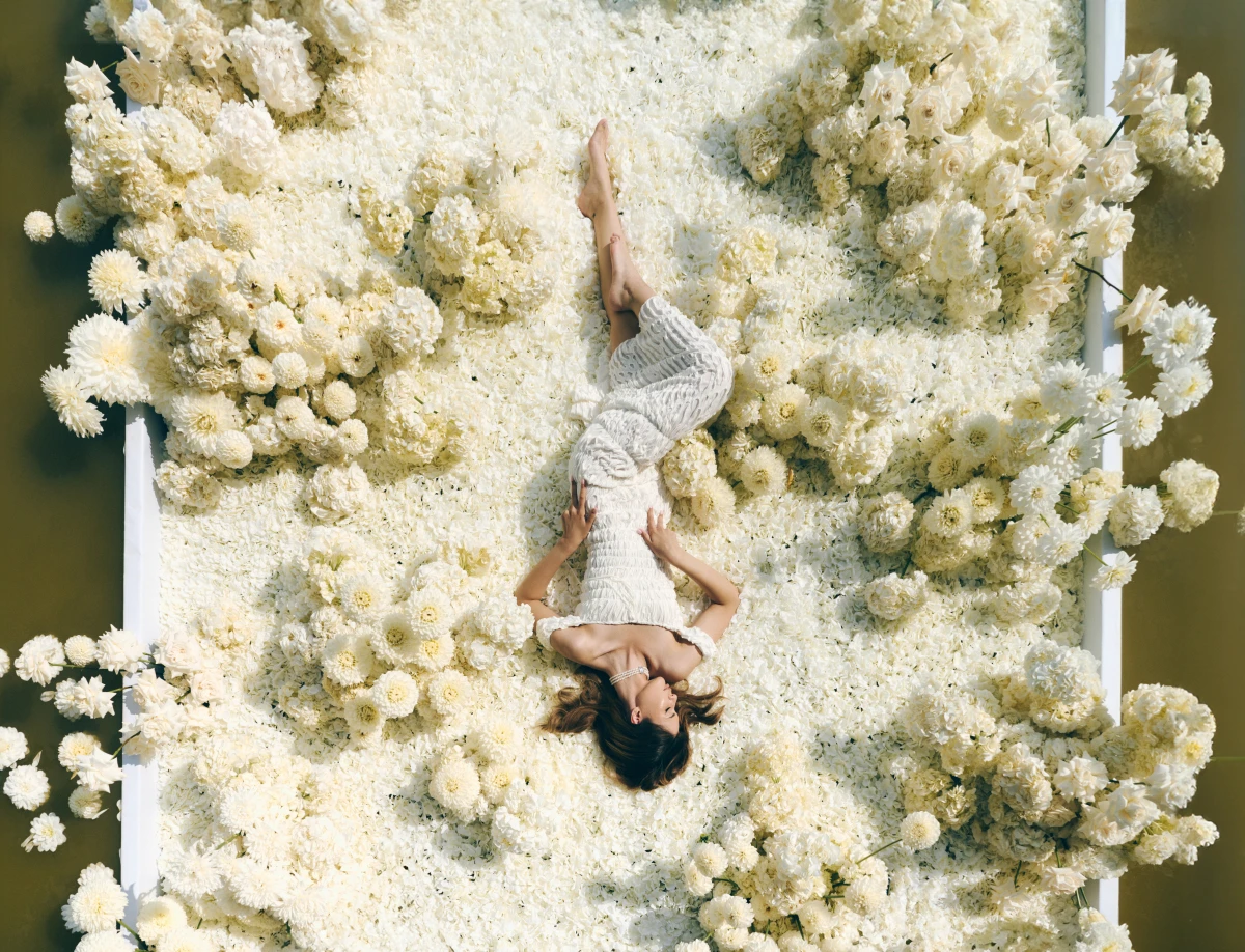босая девушка отдыхает среди пышных белых соцветий, снято с высоты птичьего полёта