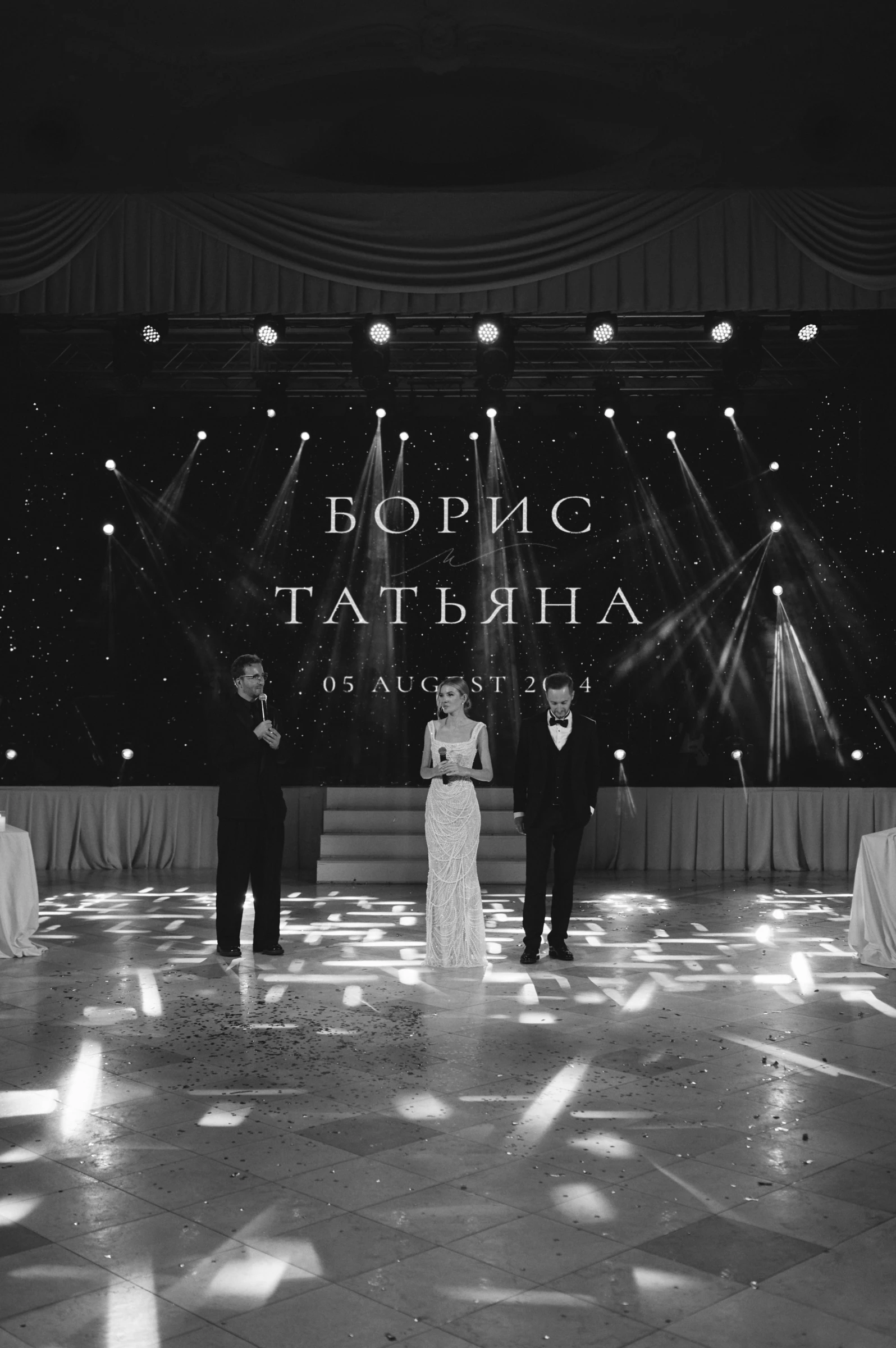 Трое стоят на танцполе, отражённом бликами света в глянцевой плитке