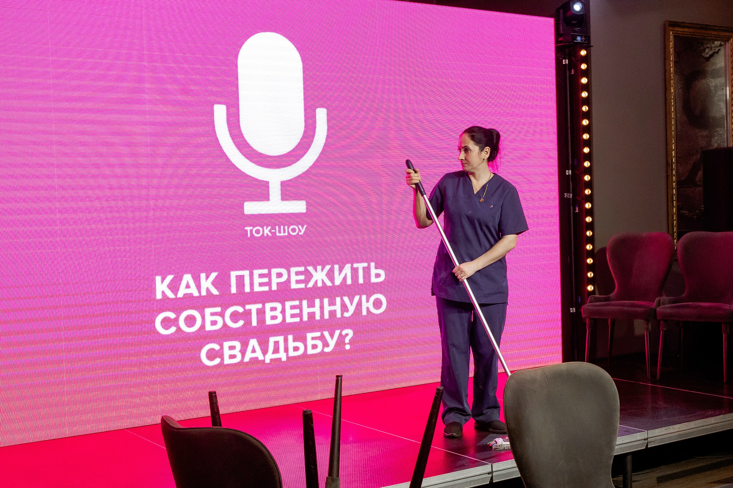 Сцена с креслами и большим цифровым баннером розового цвета на празднике